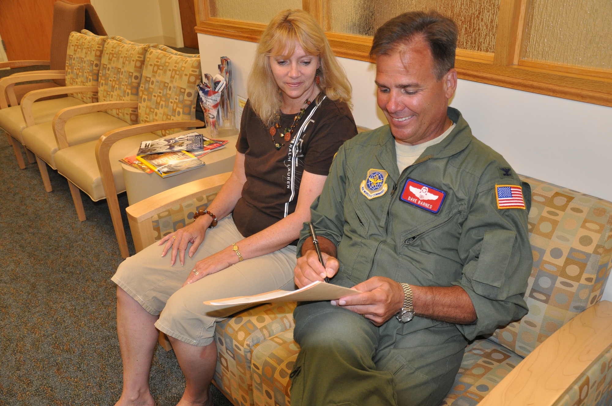 Col. David Barnes, 618th Air and Space Operations Center (Tanker Airlift Control Center) senior director of operations, signs his waiver to remain on flight status with the support of his wife, Kelly. The waiver signified Barnes' "note to normal" after his diagnosis with cancer. (U.S. Air Force photo/Staff Sgt. Amber R. Kelly-Herard)