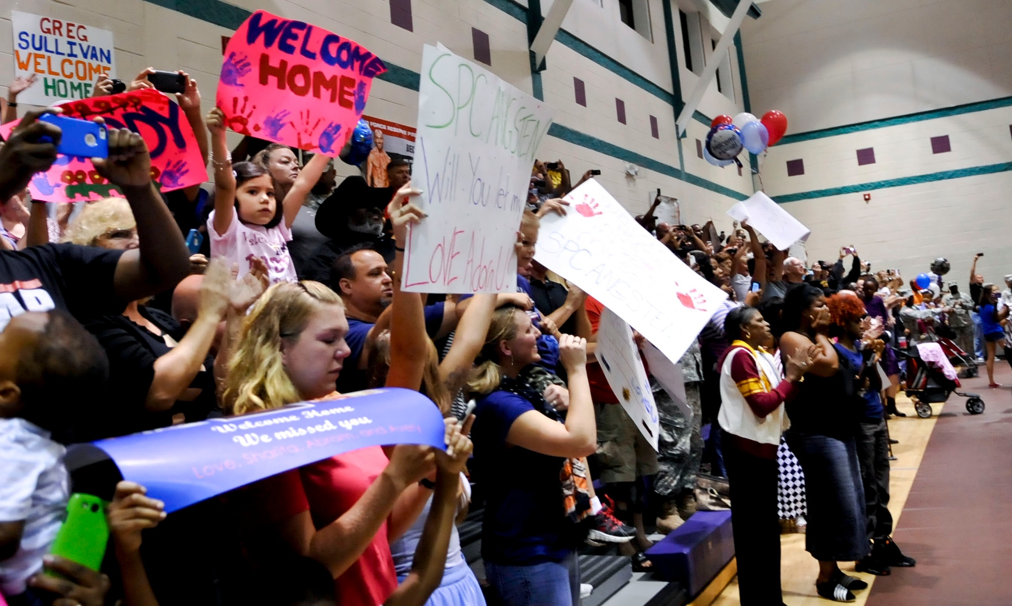 Family members stand holding signs and cheering as members of the 359th Inland Cargo Transfer Company make their appearance at a welcome-home ceremony at Fort Eustis, Va., Sept. 9, 2013. The 359th ICTC is returning from a nine-month deployment. (U.S. Air Force photo by Staff Sgt. Wesley Farnsworth/Released)