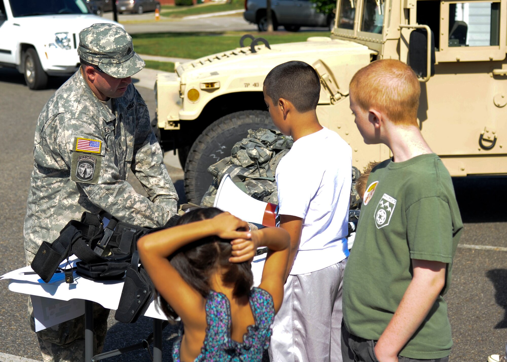U.S. Army Staff Sgt. Kenneth Finney, 221st Military Police Detachment arms specialist, shows children the different equipment MPs use on post and overseas, Sept. 7,  2013, at Fort Eustis, Va. Children also had an opportunity to wear some of the equipment and climb into a Humvee’s gunner well. (U.S. Air Force photo by Airman 1st Class Austin Harvill/Released)