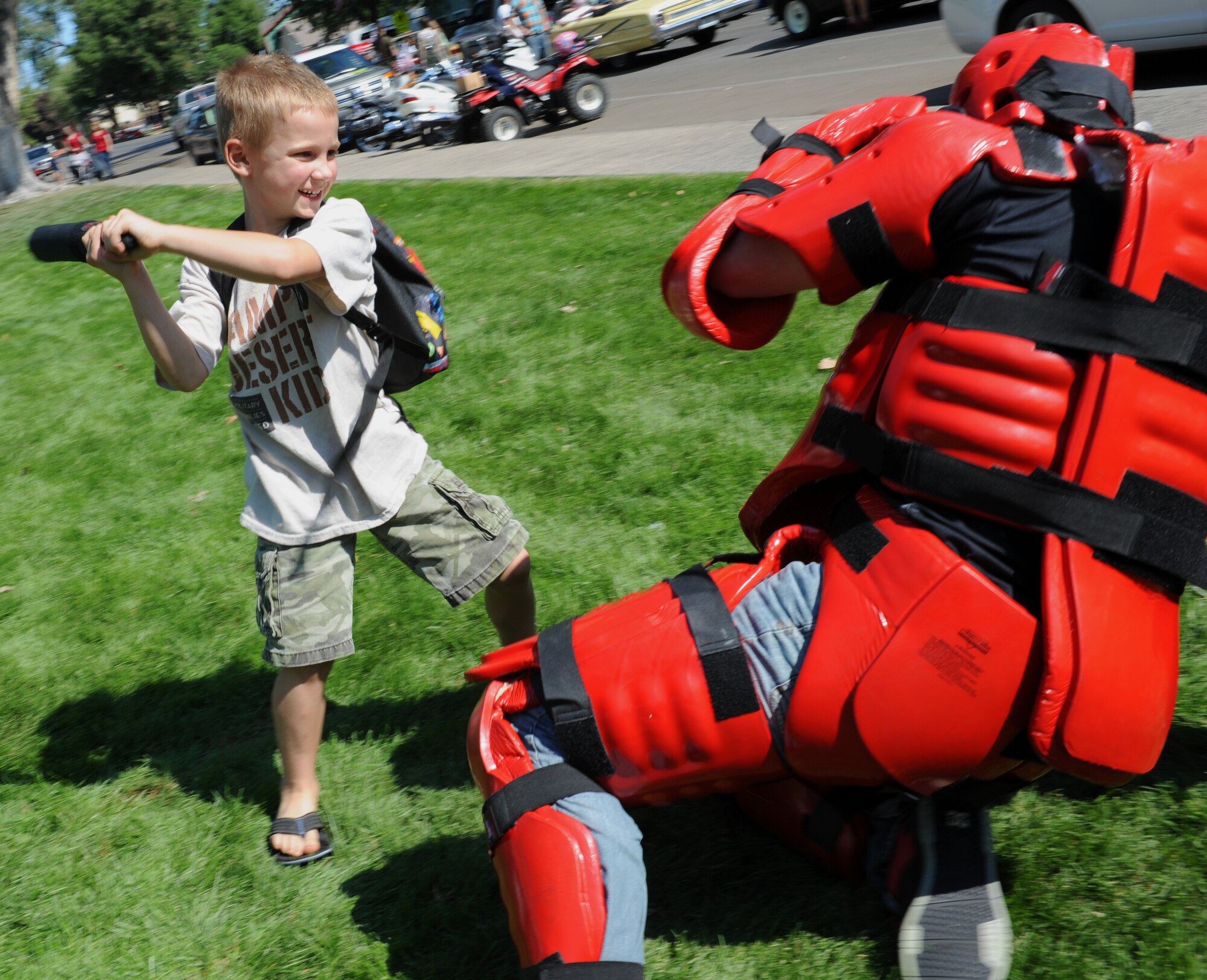 A child attacks a "red man" during the Air Force Appreciation Days parade Sept. 7, 2013, in Mountain Home, Idaho. Military personnel from the 366th Fighter Wing wore the combat training suit allowing children to attack them with a training baton. (U.S. Air Force photo by Senior Airman Benjamin Sutton/Released)