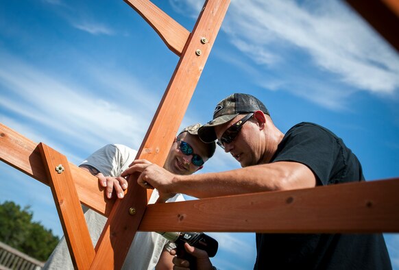 (Left) Staff Sgt. Jonathan Garrett, 628th Security Forces Squadron military working dog handler, and Staff Sgt. Blake Garrett, 628th SFS MWD handler, construct a swing set for a deployed Wingman’s daughter. Staff Sgt. Kyle Shaughnessy, 628th SFS MWD handler, is currently deployed to Southwest Asia. His fellow Airmen built the swing set in accordance with the Trident United Way’s Day of Caring events occurring throughout Joint Base Charleston, where approximately 2,500 service members from the base volunteered their skills to assist with more than 50 projects in the local community. The base held their volunteer events a week earlier than Trident the Day of Caring, due to operational commitments including the delivery of the final U.S. Air Force C-17 Globemaster III.