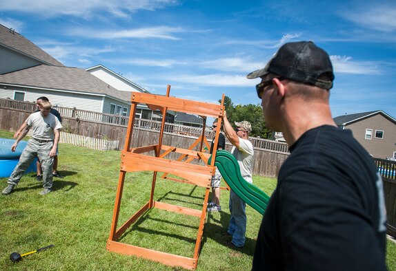 Staff Sgt. Blake Garrett, 628th Security Forces Squadron military working dog handler, looks on as Airmen from the 628th SFS build a swing set for a deployed Wingman’s daughter. Staff Sgt. Kyle Shaughnessy, 628th SFS MWD handler, is currently deployed to Southwest Asia. His fellow  Airmen built the swing set in accordance with the Trident United Way’s Day of Caring events occurring throughout the base, where approximately 2,500 servicemembers volunteered their skills to assist with more than 50 projects in the local community. The base held their volunteer events a week earlier than United Way's Day of Caring, due to operational commitments including the  the delivery of the final U.S. Air Force C-17 Globemaster III. (U.S. Air Force Photo / Senior Airman Tom Brading)