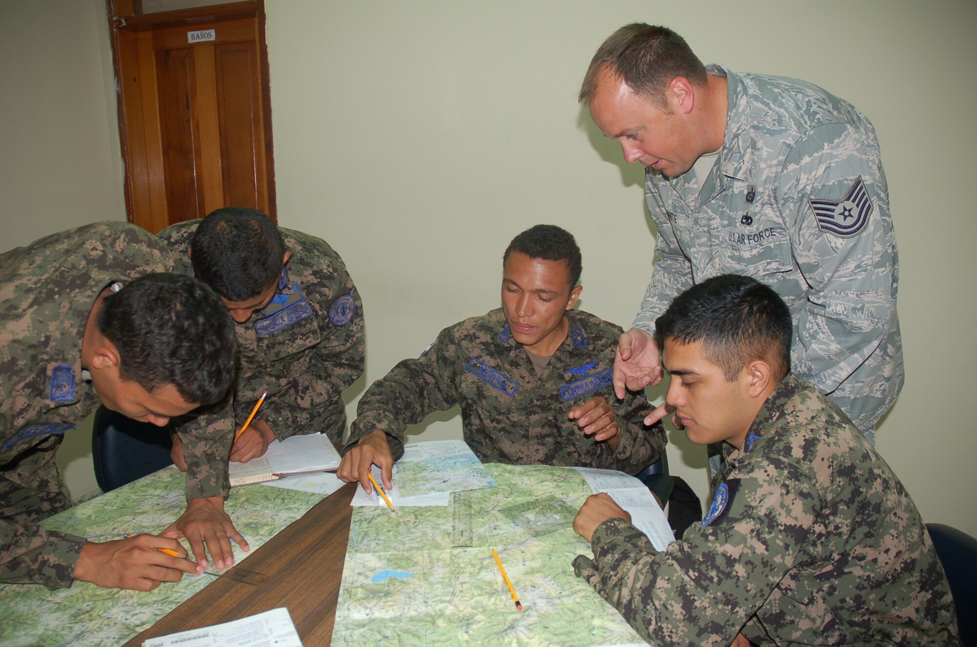 Technical Sgt. Christopher White, 571st Mobility Support Advisory Squadron intelligence air advisor, provides guidance and instruction on plotting points in geographic latitude/longitude and military grid reference system to members of the Honduran Air Force during the MSAS Building Partner Capacity mission, Jul 29 – 24 Aug, at Base Aerea Hector Acosta Mejia, Tegucigalpa, Honduras. (U.S. Air Force photo by Major Lorena Tejada)