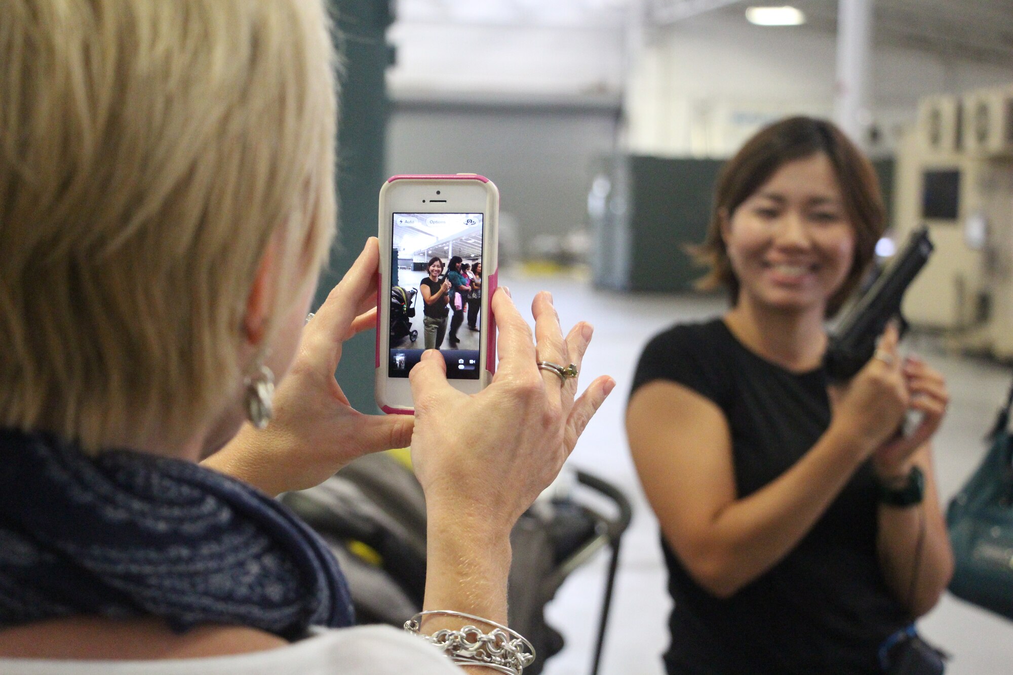 JOINT BASE MCGUIRE-DIX-LAKEHURST, N.J – Angela Niederer, wife of Lt. Col. Justin Niederer, 817th Global Mobility Squadron commander, captures the pistol packing pose of Akiko Diaz, wife of 1st Lt. John Diaz at a demonstration at the Global Reach Deployment Center during the Spouse’s Orientation Day Sep. 6, 2013. This event introduced 621st Contingency Response Wing families to one another and provided an inside look at CRW operations. (U.S. Air Force photo by Senior Airman Destinie M. Chavez/released)