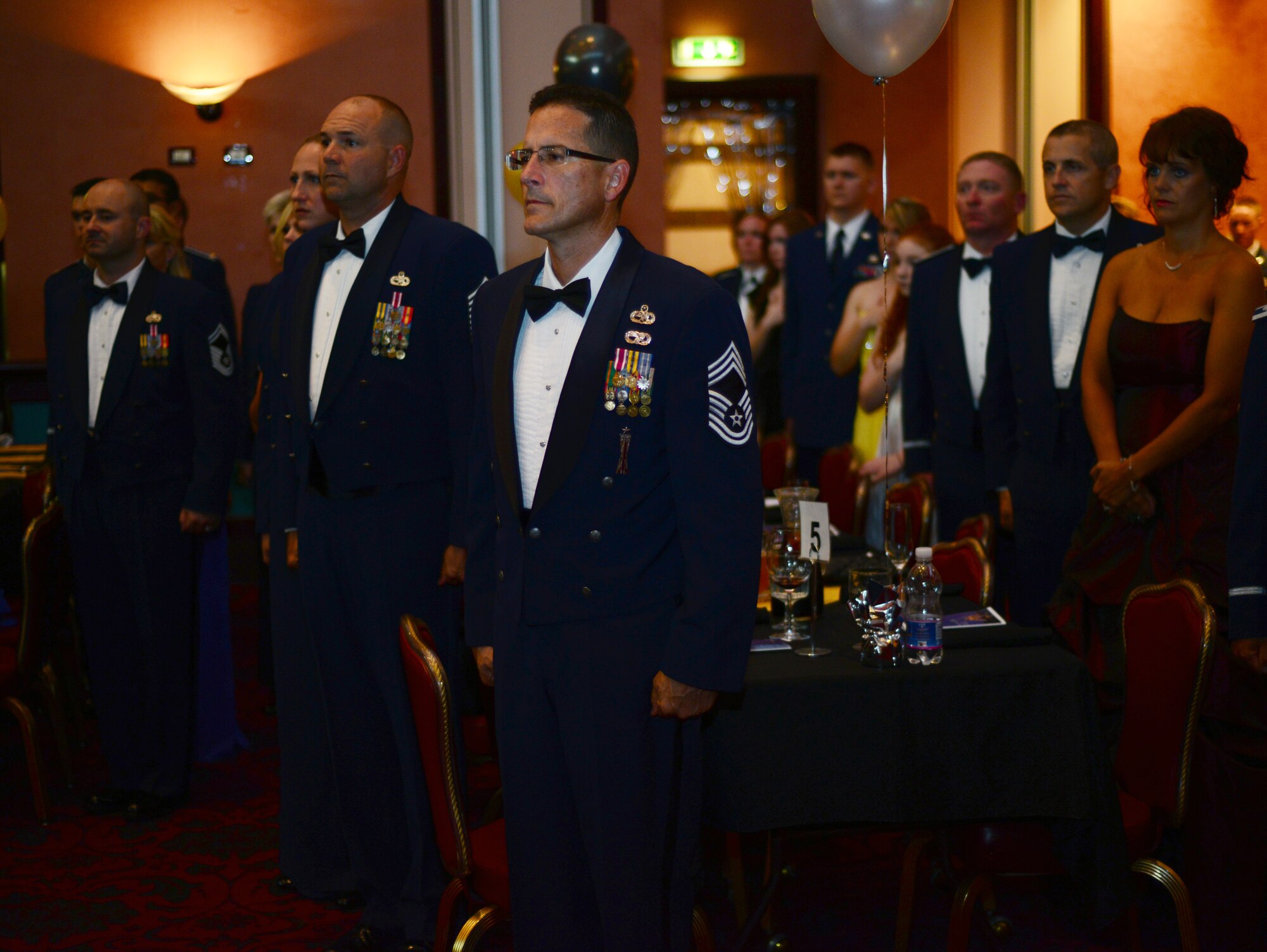 Service members and their families pay respect to the U.S. Flag during the playing of the National Anthem at the Aviano Air Force Ball Sept. 6, 2013, at Aviano Air Base, Italy. Each year, Airmen celebrate the birth of the Air Force during the month of September with a formal ball that highlights the traditions of the U. S. Air Force with speeches, toasts and remembrance of service members past and present. This is the 66th Anniversary of the U.S. Air Force. (U.S. Air Force photo/Senior Airman Michael Battles)