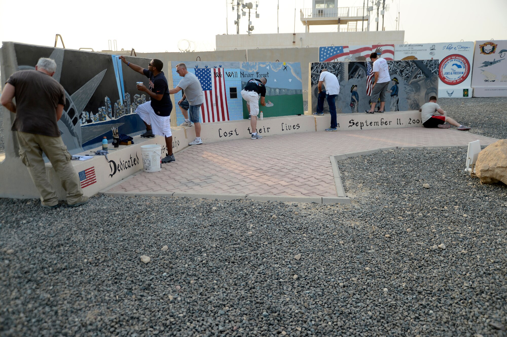Members of the 386th Air Expeditionary Wing work together to restore a memorial here, Sep 5, 2013. The memorial is the September 11 tri-wall that was initially painted in 2008. The first sergeants took the project on and with 13 volunteers from around the base, 2.5 gallons of paint and more than 150 man hours the project is finished. The project will be completed once there is a clear have a finishing coat in an attempt to preserve the memorial for years to come.  (U.S. Air Force photo by Master Sgt. Christopher A. Campbell)
