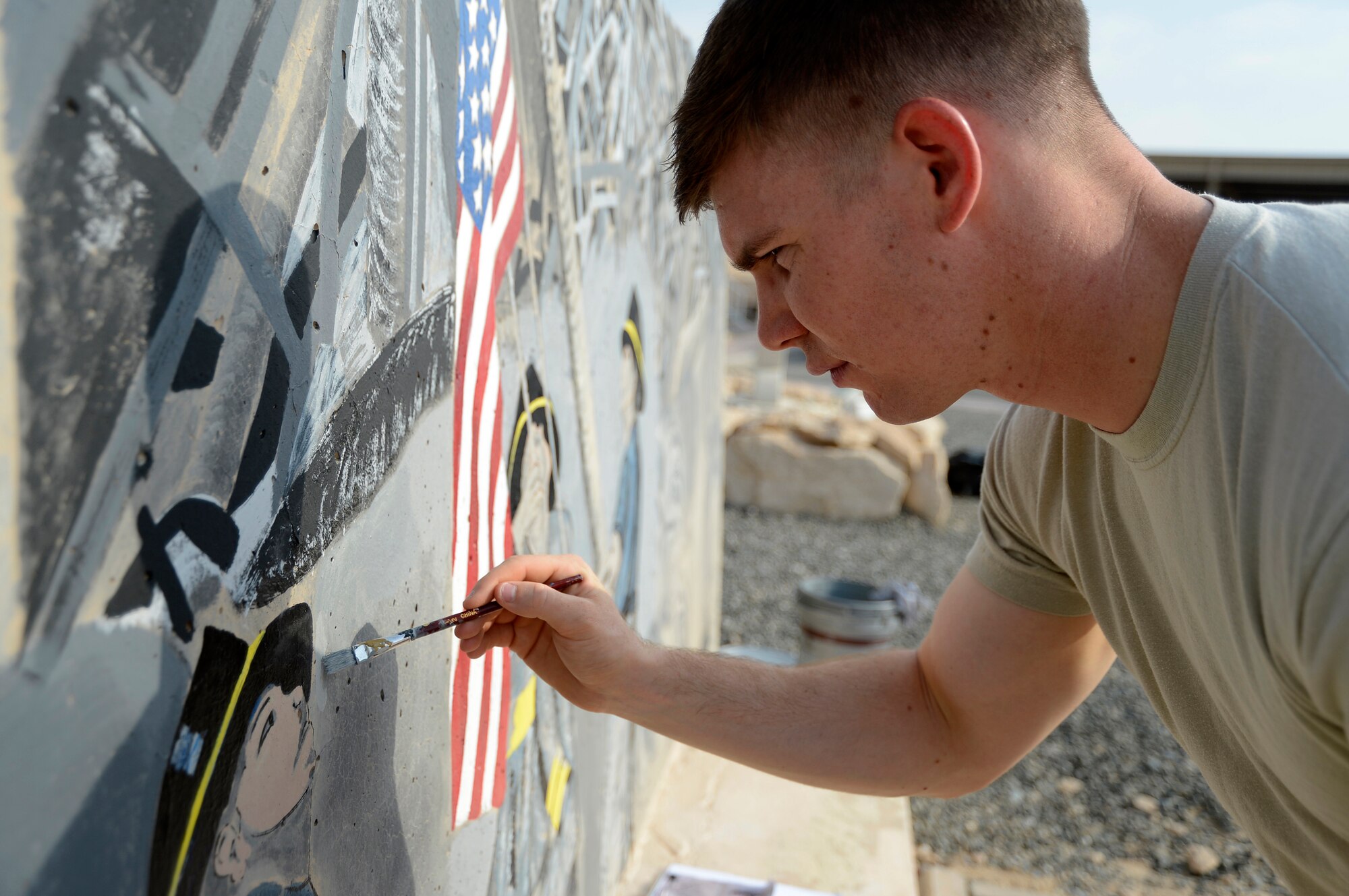 Senior Airman Steven Bultemeier, 386th Expeditionary Communications Squadron, telephone maintenance and client service technician, repaints a memorial mural here, Sept. 5, 2013. The memorial is the September 11 tri-wall that was initially painted in 2008. Bultemeier is one of 13 volunteers helping to resurrect the memorial. Bultemeier is deployed from Joint Base Lewis-McChord, Wash., and is a native of Castle Rock, Colo. (U.S. Air Force photo by Master Sgt. Christopher A. Campbell)