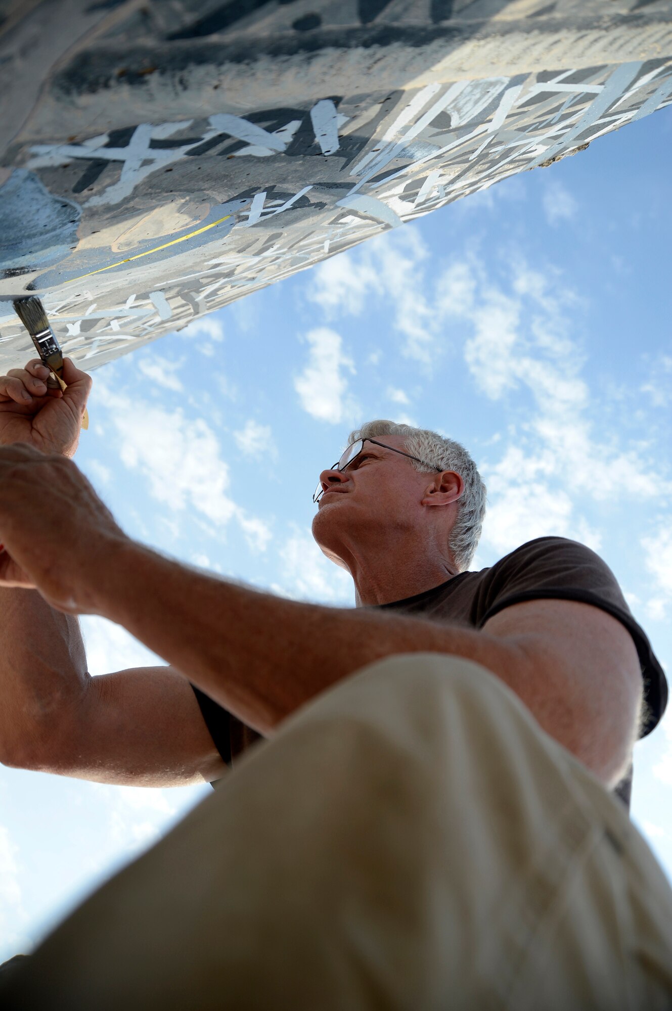 Mr. Mike May, 386th Expeditionary Communications Squadron, telephone installation and repair contractor, restores a memorial mural here, Sept. 5, 2013. The memorial is the September 11 tri-wall that was initially painted in 2008. May is restoring the memorial that has degraded due to the years of wear and tear. He also has researched the images used to create the walls and is making minor changes to make the walls a little more authentic. May, a native of Tampa, Fla., was asked by the first sergeants to work with them to bring the memorial back to life. (U.S. Air Force photo by Master Sgt. Christopher A. Campbell)