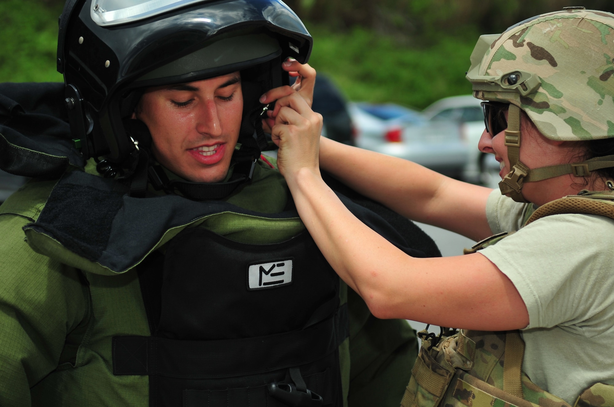 U.S. Air Force Senior Airman Erica Demattei Hopper assists Staff Sgt. Michael Vallejo, both 18th Civil Engineer Squadron Explosive Ordnance Disposal technicians, with his helmet for a bomb disposal suit in response to a suspicious bag during a local operational readiness exercise on Kadena Air Base, Japan, Sept. 10, 2013. The 18th CES Explosive Ordnance Disposal flight responds to more than 50 disposal operations a year, to include disposing World War II ordnance still found on Okinawa. (U.S. Air Force photo by Staff Sgt. Amber E. N. Jacobs)