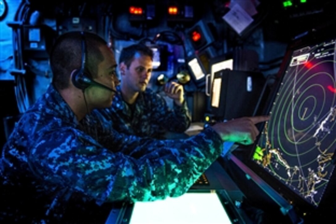 U.S. Navy Petty Officer 2nd Class Jared Regala, left, trains Navy Petty Officer 2nd Class Mitchell Mason on proper procedures for tracking radar signatures in the air traffic control center aboard the amphibious assault ship USS Bonhomme Richard during Exercise Koolendong 2013 off of Australia, Sept. 6, 2013. 