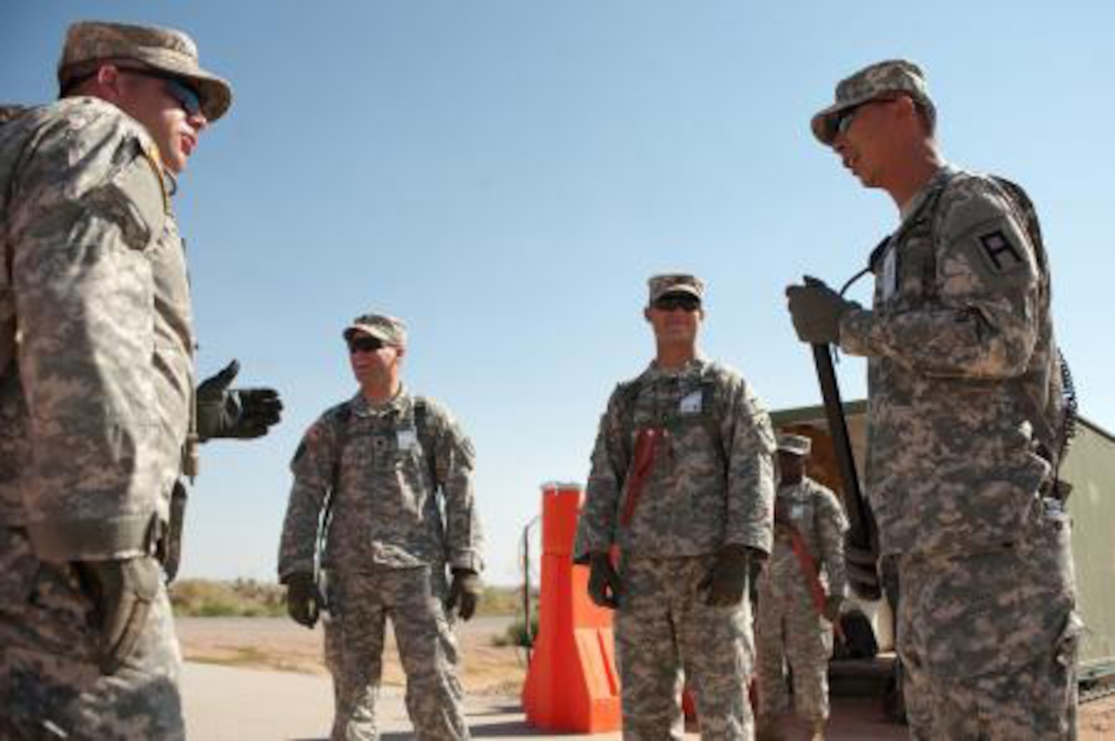 Staff Sgt. Johan Pae, right, an observer controller/trainer with Division West's 5th Armored Brigade, talks with soldiers of the Maine Army National Guard's 488th Military Police Company at the detainee operations training facility at Camp McGregor, N.M., last month.