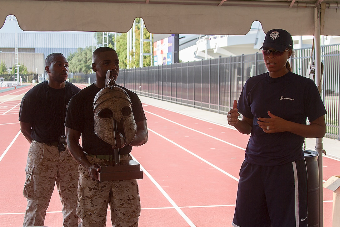 Capt. Adesina Aladetohun, Officer Selection Officer for Recruiting Station Baton Rouge, holds an award for Nikki Caldwell, head coach of Louisiana State University women’s basketball team, and her team after completing the combat fitness course on the track and field at LSU in Baton Rouge, La., Sept 9, 2013. Marines from Officer Selection Team Baton Rouge, and surrounding area joined together with the women’s basketball team from LSU to complete a combat fitness course not just once, but twice, and helping them push themselves to a higher limit, setting the bar above other colleges. The event instilled in the athletes Marine Corps leadership values and teamwork that the players can use both on and off the court. (U.S. Marine Corps photo by Lance Cpl. John-Paul Imbody)