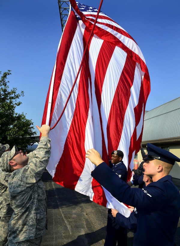 Airmen from the 436th Civil Engineer Squadron and 436th Security Forces Squadron raise the flag in honor of the victims of 9/11, on Sept. 11, 2013, at Dover Air Force Base, Del. The memorial incorporates two pieces of steel from World Trade Center tower one, a rock from the United Airlines Flight 93 crash site and a block from the damaged portion of the Pentagon. (U.S. Air Force photo/David S. Tucker)