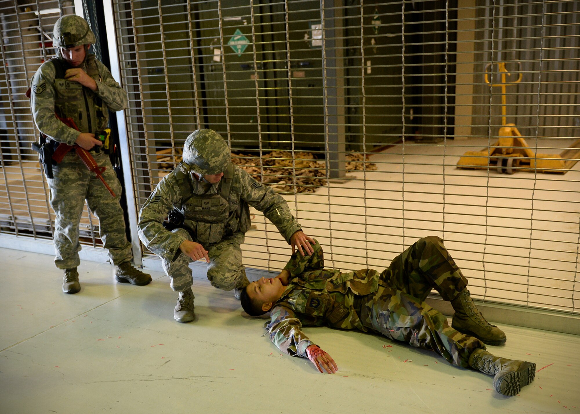 Staff Sgts. Philip Maxwell (left), 354th Security Forces Squadron flight lead, and Joseph Wake (middle), 354th SFS military working dog handler, tend to a simulated active shooter victim during an exercise Sept. 10, 2013, Eielson Air Force Base, Alaska. Emergency responders quickly apprehended the suspect during the scenario, which is part of the Pacific Air Forces Readiness Focused Consolidated Unit Inspection to evaluate the base on readiness and compliance with operational instructions. (U.S. Air Force photo by Senior Airman Shawn Nickel/Released)