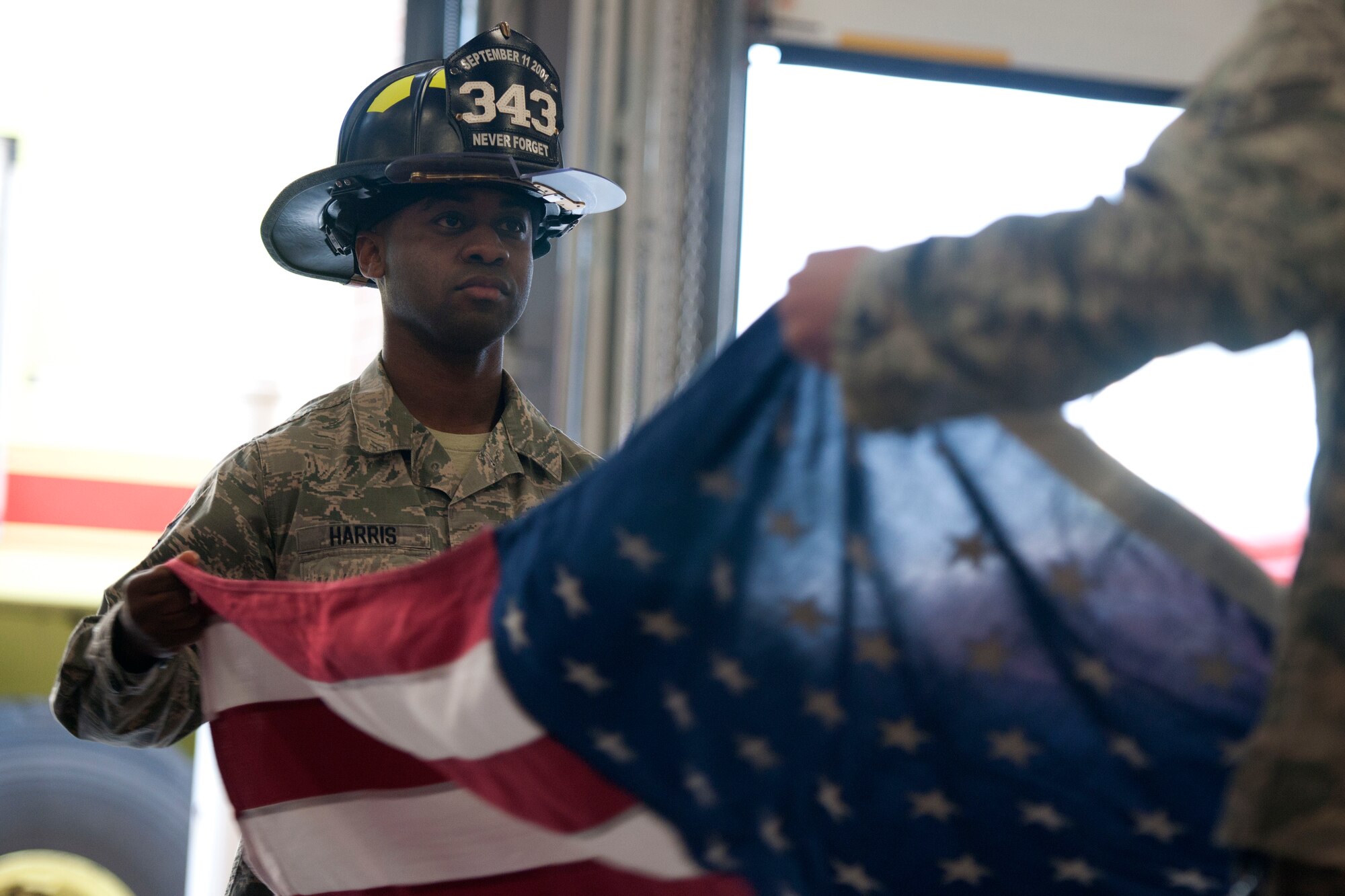 ALTUS AIR FORCE BASE, Okla. – Tech. Sgt. Allen Harris, 97th Civil Engineer Squadron firefighter, folds a flag during a 9/11 remembrance ceremony Sept. 11 at the base fire department. 97th Security Forces Squadron and the 97th Civil Engineer Squadron held a 9/11 remembrance ceremony in honor of the emergency responders who lost their lives Sept. 11, 2001. (U.S. Air Force Photo by Senior Airman Jesse Lopez / Released)