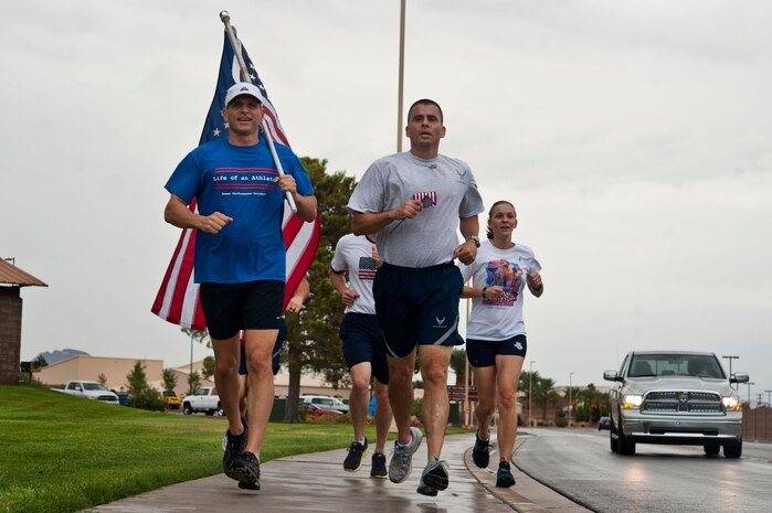 U.S. Air Force Col. Barry Cornish (left), 99th Air Base Wing commander, and Chief Master Sgt. Steven Cleveland (right), 99th Air Base Wing command chief, run during the 9/11 Old Glory Challenge Sept. 11, 2013, at Nellis Air Force Base, Nev. Teams from around the base ran in 30 minute increments around Freedom Park to keep the American flag flying from 6 a.m. to 4:30 p.m. The event is a tribute to the victims of the terrorist attacks that took place on 9/11. The event was sponsored by the Top III and Team Red White and Blue Las Vegas. (U.S. Air Force photo by Senior Airman Daniel Hughes)