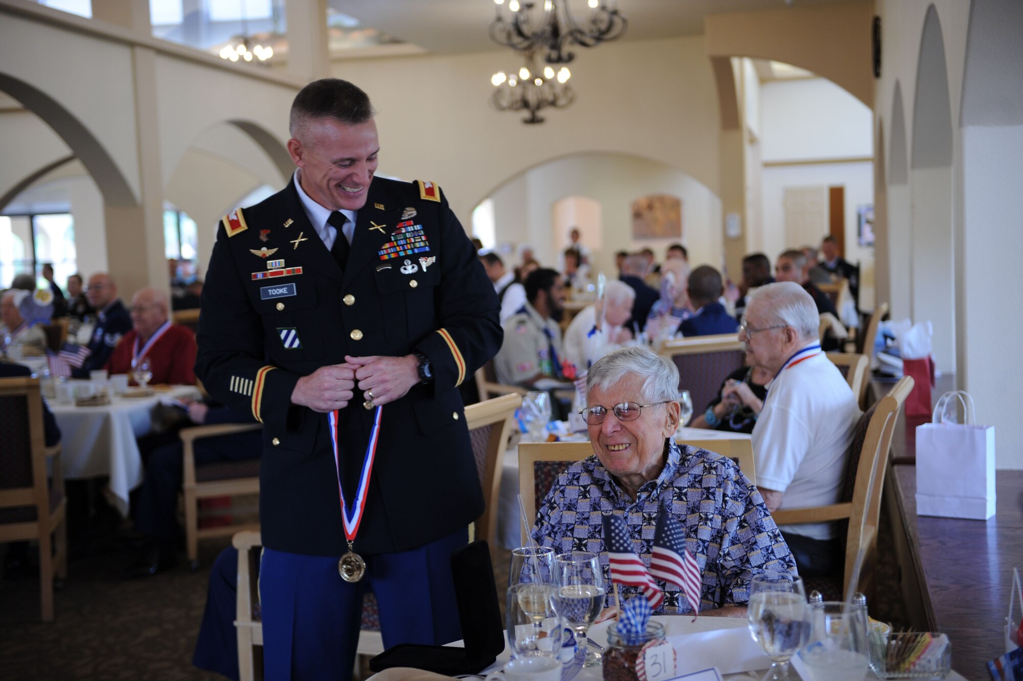 U.S. Army Col. Shaun Tooke, 1st Battlefield Coordination Detachment commander, prepares to present a World War II medallion to Jack Proctor at a World War II Veterans Medallion Ceremony held at Silver Springs Senior Living Community in Green Valley, Ariz., Sept. 7, 2013. Proctor served on the U.S.S. Tombigee with the U.S. Navy during the war. (U.S. Air Force photo by Airman 1st Class Saphfire Cook/Released) 