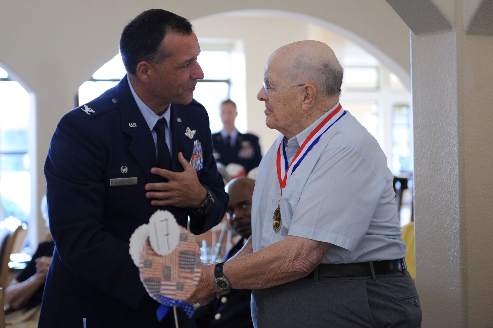 U.S. Air Force Col. Kevin Blanchard, 355th Fighter Wing commander, speaks with Robert Hamilton after presenting him with a medallion during a World War II Veterans Medallion Ceremony held at Silver Springs Senior Living Community in Green Valley, Ariz., Sept. 7, 2013. Hamilton served as a company medic with the U.S. Army during the war. (U.S. Air Force photo by Airman 1st Class Saphfire Cook/Released) (Cropped)
