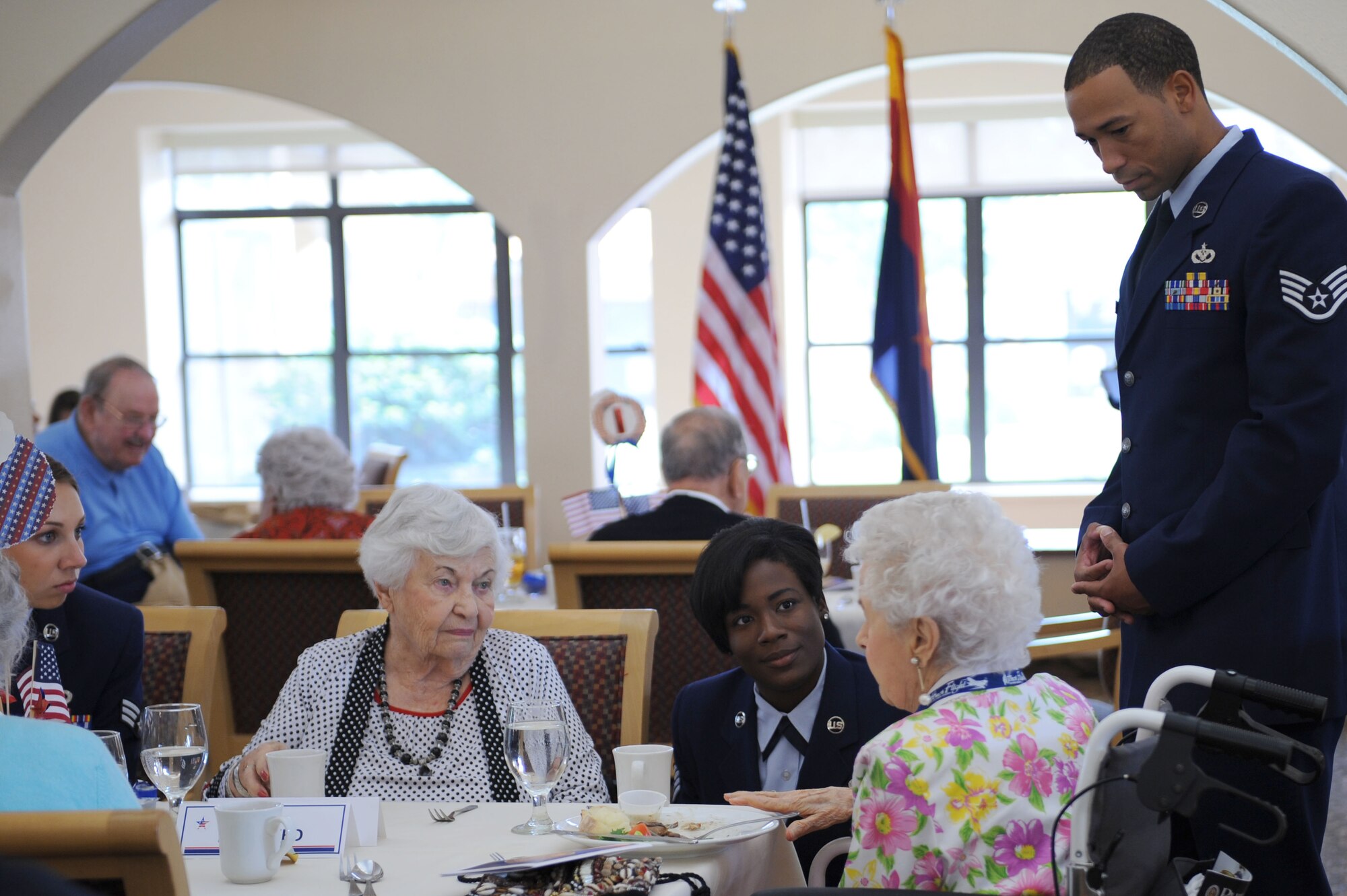 U.S. Air Force Staff Sgt. Kellie Jones and her husband, Staff Sgt. Michael Jones, medallion ceremony volunteers, talk with veterans during a World War II Veterans Medallion Ceremony held at Silver Springs Senior Living Community in Green Valley, Ariz., Sept. 7, 2013. Roughly 70 Airmen, sailors, soldiers and Marines volunteered as escorts for the veterans being honored during the ceremony. (U.S. Air Force photo by Airman 1st Class Saphfire Cook/Released) (Cropped)