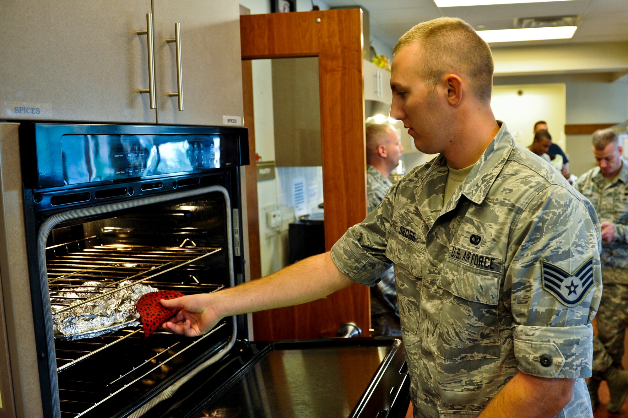 Staff Sgt. Chris Gross, 460th Space Wing Public Affairs, removes baked potatoes from an oven Sept. 10, 2013, at the Ronald McDonald House in Aurora, Colo. Fourteen Team Buckley members prepared tacos and baked potatoes for families staying at the Ronald McDonald House. The organization offers a home away from home for families needing to be near their seriously ill or injured children while they're being treated at nearby hospitals. (U.S. Air Force photo by Airman 1st Class Riley Johnson/Released)