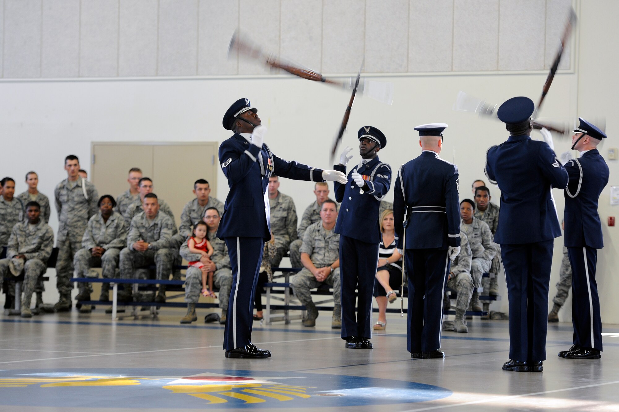 GOODFELLOW AIR FORCE BASE, Texas- The U.S. Air Force Honor Guard Drill Team hurl their 11-pound weapons over and around their drill commander during a recruiting event at the Carswell Field House Sept. 6.  The drill team aims to promote the Air Force mission by showcasing drill performances at public and military venues to recruit, retain and inspire Airmen. (U.S. Air Force photo/ Staff Sgt. Austin Knox)