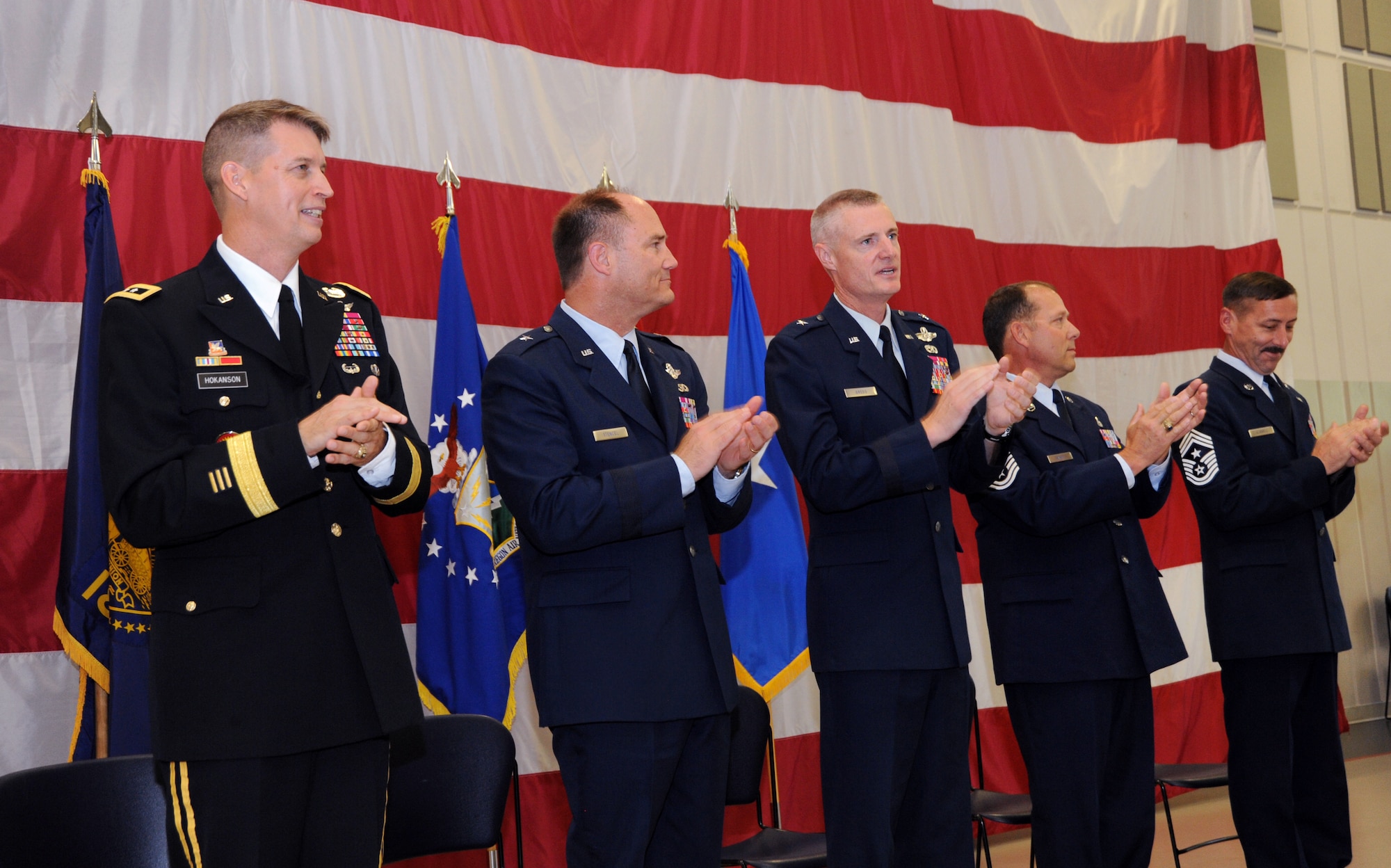 Members of the official party clap along to the Air Force Song during the closing of the Change of Command and State Command Chief Change of Authority ceremony, Oregon Air National Guard, held at the Anderson Readiness Center, Salem, Ore., Sept. 8, 2013. (left to right) Maj. Gen. Daniel Hokanson, Oregon Adjutant General, Brig. Gen. Michael Stencel, Commander, Oregon Air National Guard, Brig. Gen. Steven Gregg, outgoing Commander of the Oregon Air National Guard, State Command Chief Master Sgt. Patrick “Andy” Gauntz, Oregon Air National Guard State Command Chief, and Command Chief Master Sgt. Mark Russell, outgoing State Command Chief. (Air National Guard photo by Tech. Sgt. John Hughel, 142nd Fighter Wing Public Affairs/Released)