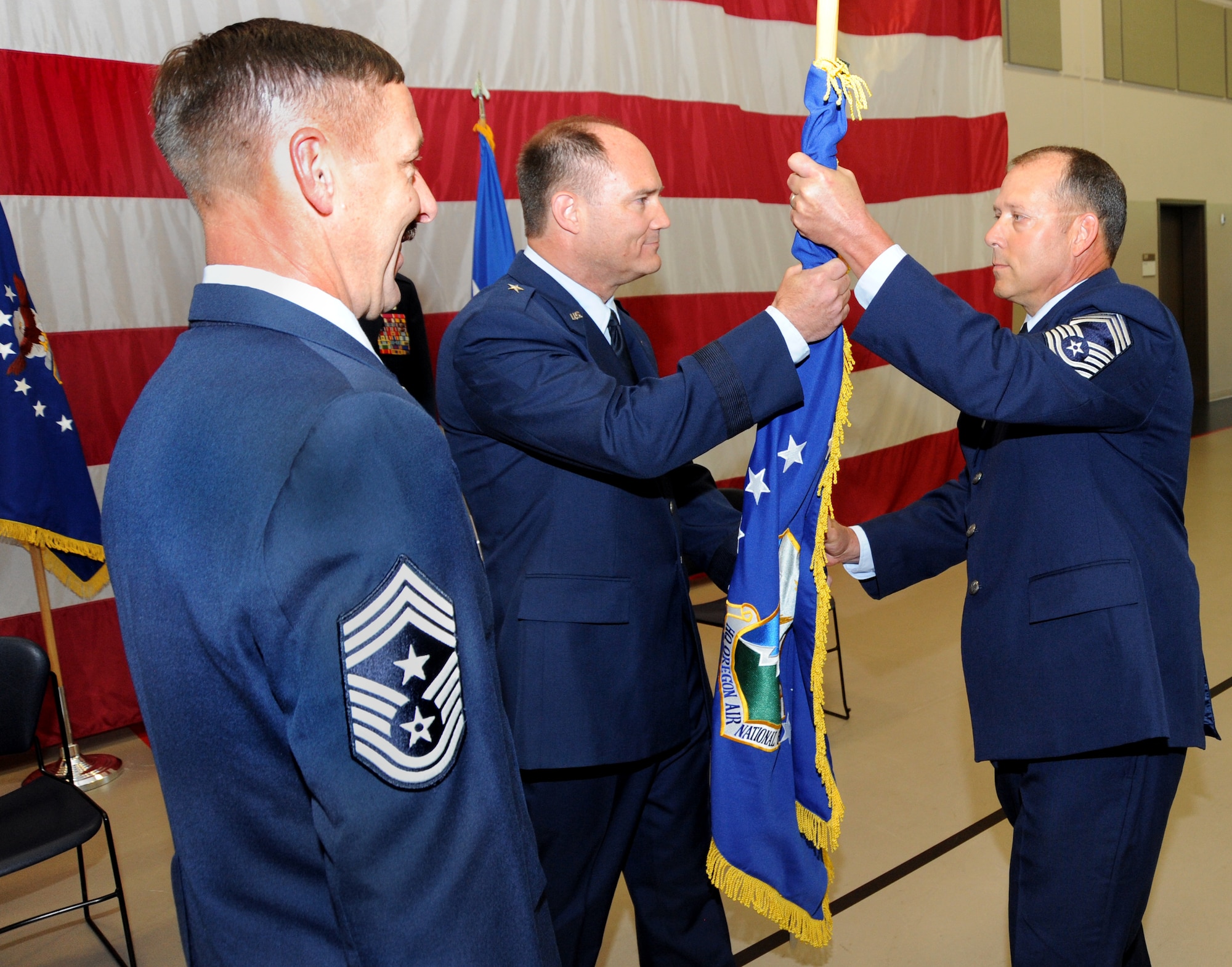 Command Chief Master Sgt. Mark Russell (left) watches Brig. Gen. Michael Stencel pass the colors of the Oregon Air National Guard Flag to Chief Master Sgt. Patrick “Andy” Gauntz, during the State Command Chief Change of Authority ceremony, held at the Anderson Readiness Center, Salem, Ore., Sept. 8, 2013. (Air National Guard photo by Tech. Sgt. John Hughel, 142nd Fighter Wing Public Affairs/Released)