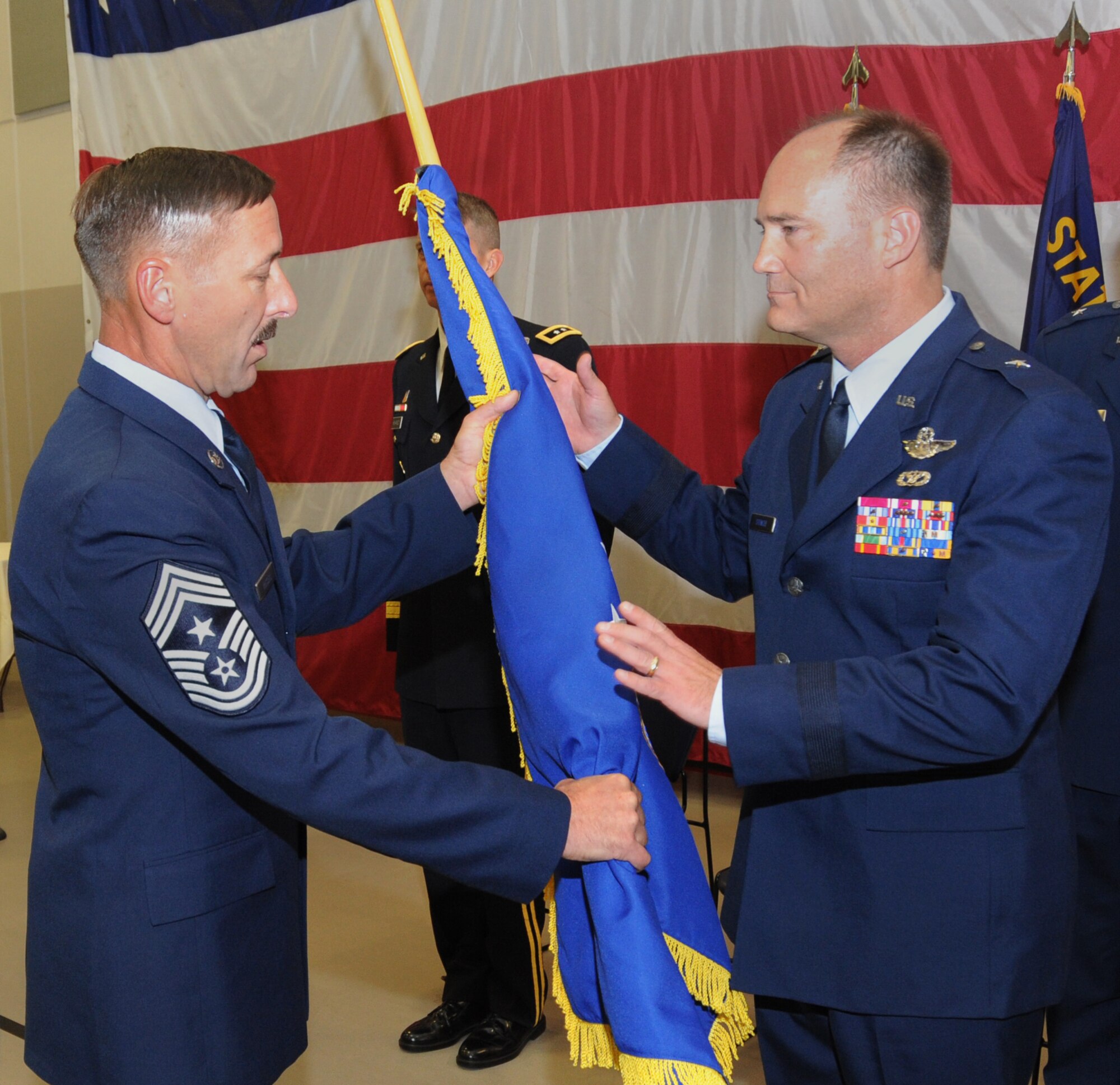 Oregon Air National Guard State Command Chief, Chief Master Sgt. Mark Russell hands the colors of the Oregon Air National Guard flag to Brig. Gen. Michael Stencel, Commander of the Oregon Air National Guard, during the State Command Chief Change of Authority ceremony, held at the Anderson Readiness Center, Salem, Ore., Sept. 8, 2013. (Air National Guard photo by Tech. Sgt. John Hughel, 142nd Fighter Wing Public Affairs/Released) 