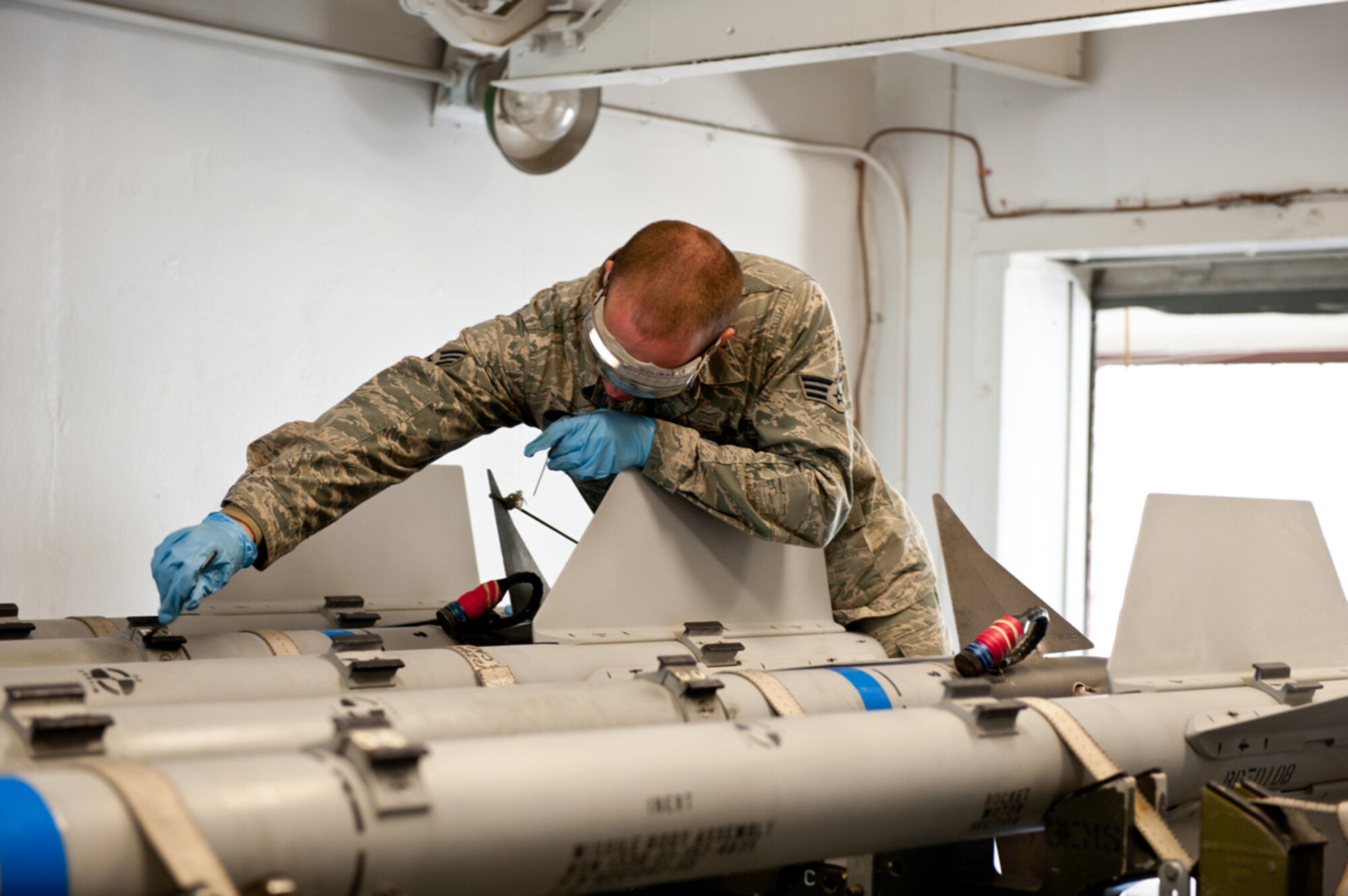 Senior Airman Joseph Liptak, assigned to the 3rd Munitions Squadron, Precision Guided Munitions Crew Chief in Production Flight, conducts maintenance on a Captive Air Training Missile AIM-9 missile, June 7, 2013. He is coating the hanger with solid film. This substance is like a paint, but protects the hangers and allows the missile to slide on and off easily from the jet's hangers.  (U.S. Air Force photo by Johnathon Green/released)