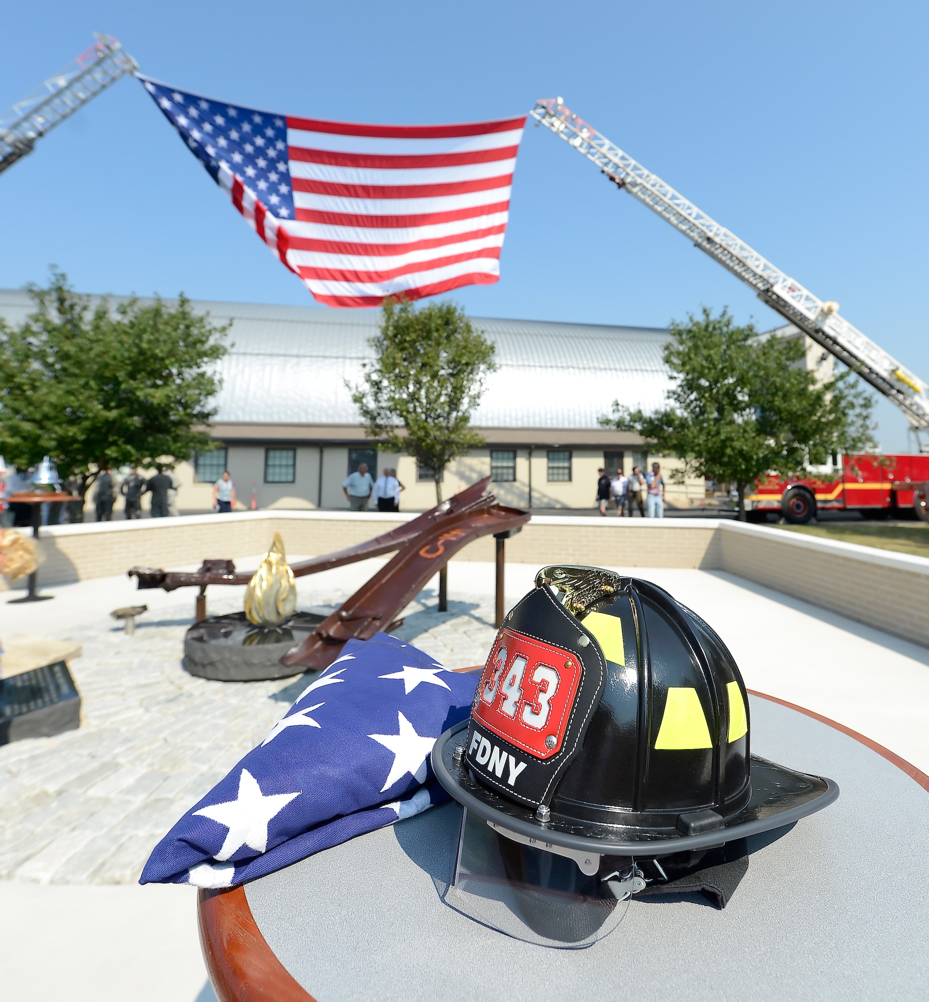A firefighters helmet from the New York Fire Department along with a folded flag are visible sitting on a table next to the newly unveiled memorial to those killed on Sept. 11, 2001, at the Air Mobility Command museum Sept. 11, 2013, at Dover Air Force Base, Del. The memorial, which incorporates two pieces of steel from World Trade Center tower one, a rock from the United Airlines Flight 93 crash site and a block from the damaged portion of the Pentagon, makes Delaware the 50th and final state to have a public memorial. The steel was acquired through the Port Authority of New York and New Jersey World Trade Center steel program. (U.S. Air Force photo/Greg L. Davis)