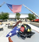 A firefighters helmet from the New York Fire Department along with a folded flag are visible sitting on a table next to the newly unveiled memorial to those killed on Sept. 11, 2001, at the Air Mobility Command museum Sept. 11, 2013, at Dover Air Force Base, Del. The memorial, which incorporates two pieces of steel from World Trade Center tower one, a rock from the United Airlines Flight 93 crash site and a block from the damaged portion of the Pentagon, makes Delaware the 50th and final state to have a public memorial. The steel was acquired through the Port Authority of New York and New Jersey World Trade Center steel program. (U.S. Air Force photo/Greg L. Davis)