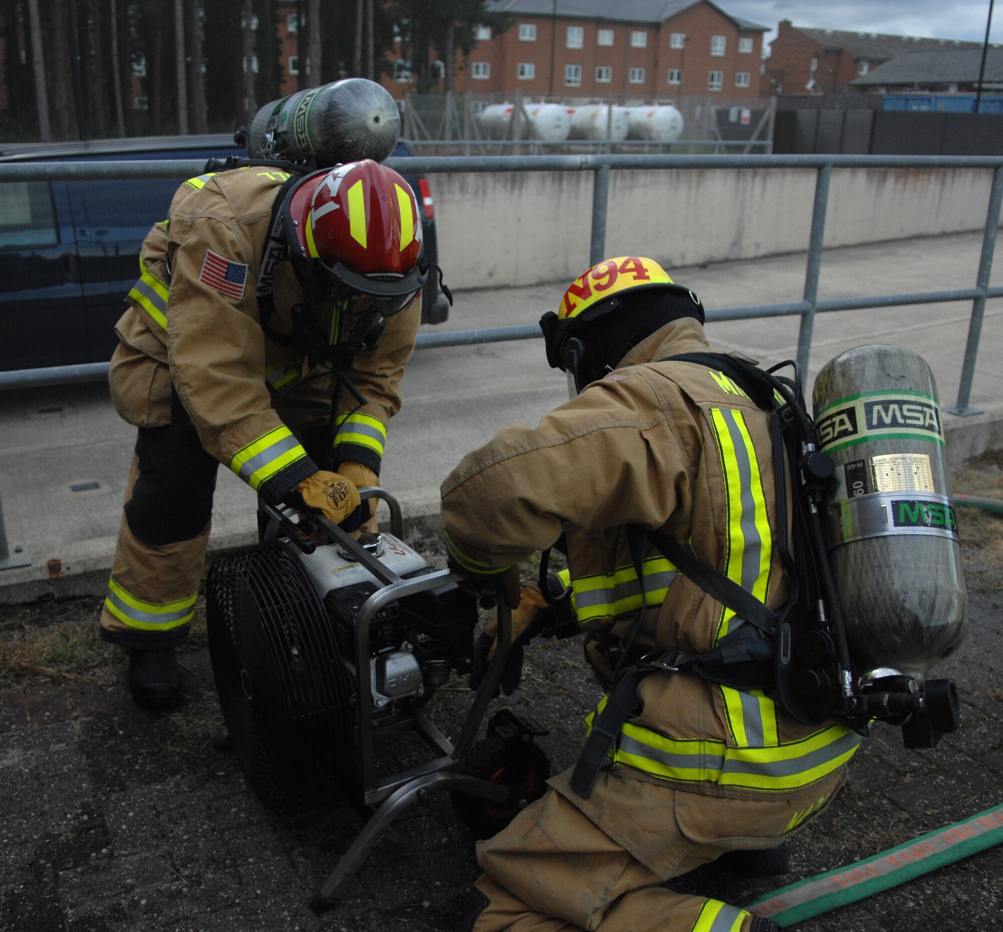 Andrew Nash, right, and U.S. Air Force Staff Sgt. Thomas Kiefer, 100th Civil Engineer Squadron Fire Department firefighters, set up a high powered fan Sept. 9, 2013, outside the post office on RAF Mildenhall, England. Firefighters responded to a simulated fire in the post office as part of an operational readiness inspection for RAF Mildenhall.  The fan offered firefighters an expeditious way to clear the fake smoke from the post office. (U.S. Air Force photo by Airman 1st Class Dillon Johnston/Released)