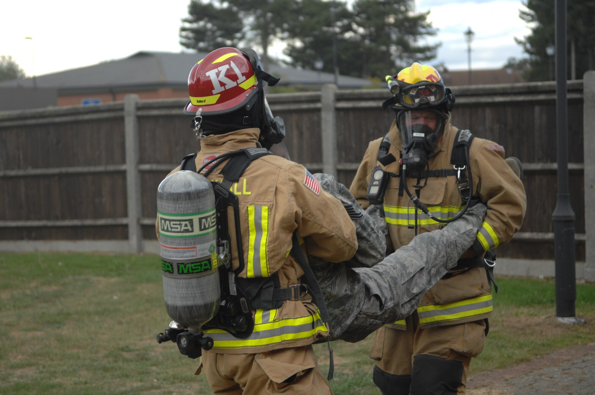 Jeremy Myles, right, and U.S. Air Force Staff Sgt. Thomas Kiefer, 100th Civil Engineer Squadron Fire Department firefighters, carry U.S. Air Force Tech. Sgt. Melvin Adkins, 100th Communication Squadron postmaster, Sept. 9, 2013, out of the post office on RAF Mildenhall, England. As part of an operational readiness inspection, a mock fire exercise was conducted in the post office. Firefighters rescued simulated victims and provided them with medical care. (U.S. Air Force photo by Airman 1st Class Dillon Johnston/Released)
