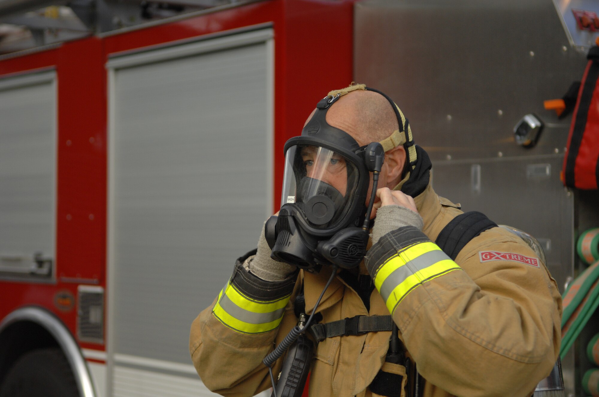 Lee Spencer, 100th Civil Engineer Squadron Fire Department crew manager, puts on his mask before entering the post office Sept. 9, 2013, on RAF Mildenhall, England. As part of an operational readiness inspection, a mock fire exercise was conducted in the post office. Firefighters responded to the incident, retrieved simulated casualties and extinguished the “fire.” (U.S. Air Force photo by Airman 1st Class Dillon Johnston/Released)
