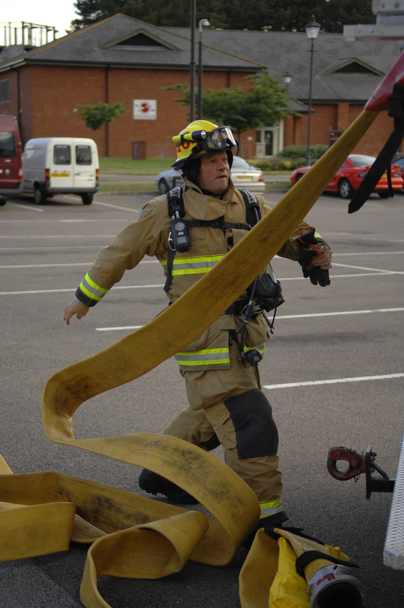 Jeremy Myles, 100th Civil Engineer Squadron Fire Department firefighter, pulls a hose off a fire truck Sept. 9, 2013, at the post office on RAF Mildenhall, England. Firefighters responded to a simulated fire in the post office as part of an operational readiness inspection for RAF Mildenhall. The post office was filled with smoke and three simulated victims were placed in the facility to test the firefighters’ search and rescue capabilities. (U.S. Air Force photo by Airman 1st Class Dillon Johnston/Released)