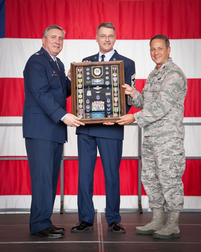 Cols. Darrell Young, and Todd McCubbin, 934th Airlift Wing commander and vice commander, present Command Chief Master Sgt. Mark Koenig, 934 AW command chief, with a gift symbolizing his military career during his retirement ceremony September 7th.  Chief Koenig retires at the Minneapolis-St. Paul Air Reserve Station, Minn., after over 33 years of service.  (U.S. Air Force photo/Shannon McKay)