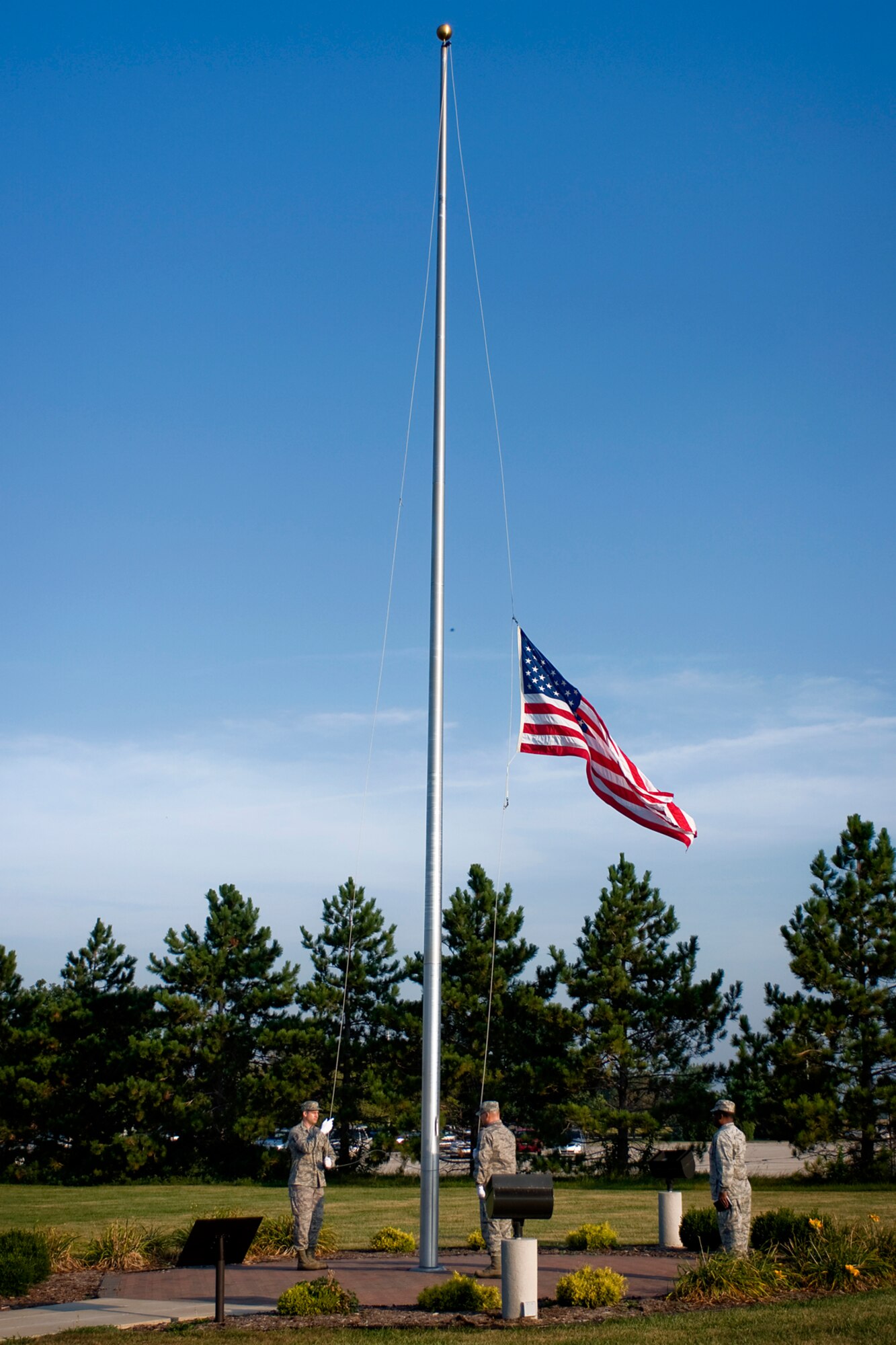 Tech. Sgts. Martin Bragg, left, and James Park, center, raise and lower a base flag to half-staff as Chaplain (Maj.) Obadiah Smith Jr. salutes during a  9/11 remembrance ceremony at Grissom Air Reserve Base, Ind., Sept. 11, 2013. Bragg is a 434th Force Support Squadron personnel specialist, Park is a 434th FSS orderly room noncommissioned officer in charge, and Smith is a 434th Air Refueling Wing chaplain. (U.S. Air Force photo/Tech. Sgt. Mark R. W. Orders-Woempner) 