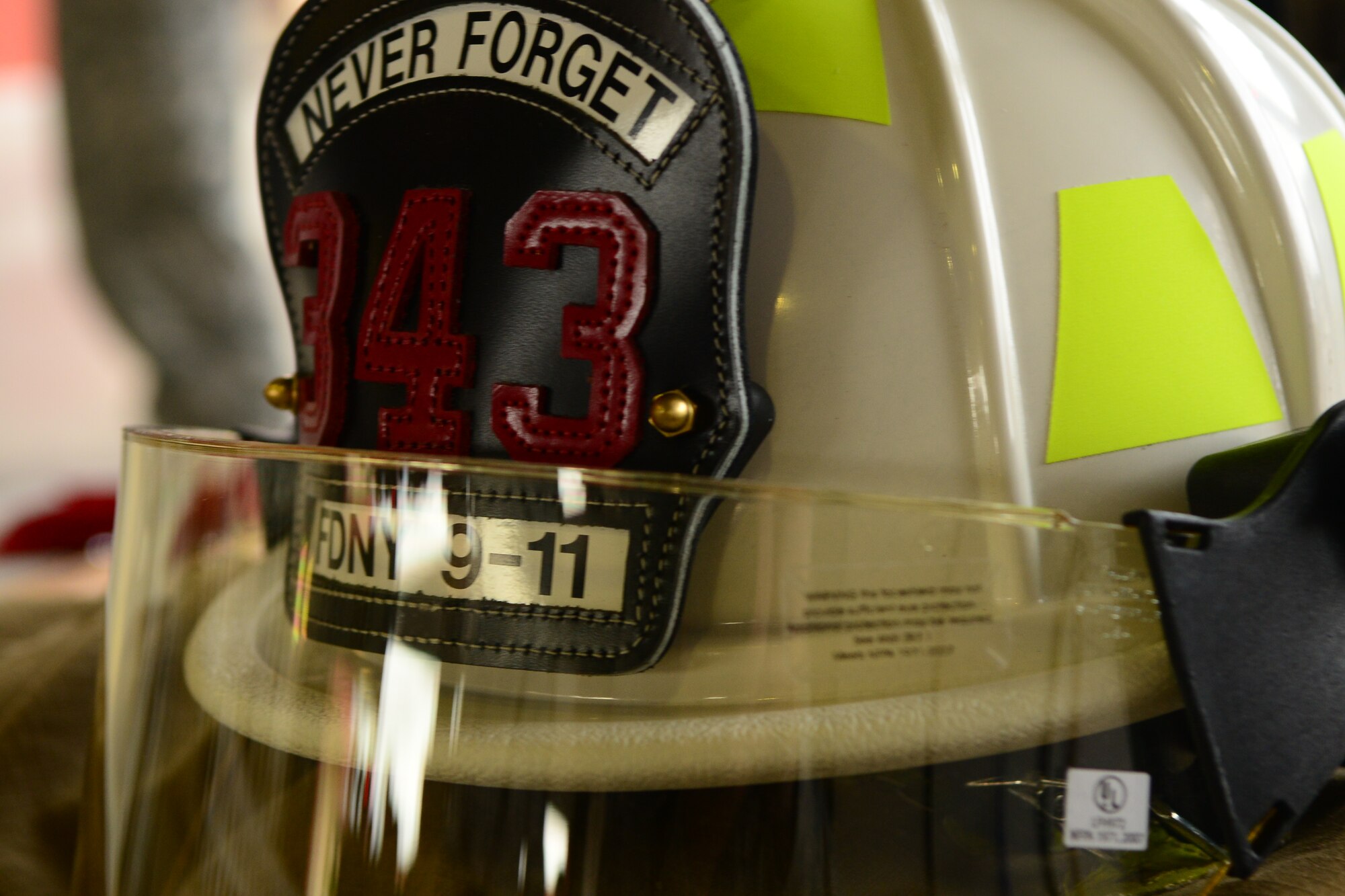 A fireman’s helmet bearing the badge “Never Forget FDNY 9-11” sits on a table during a 9/11 Remembrance Ceremony Sept. 11, 2013, at Aviano Air Base, Italy. More than 150 Team Aviano members participated in the ceremony to honor both military and civilian heroes who responded that day, and lost their lives. (U.S. Air Force photo/Senior Airman Michael Battles)