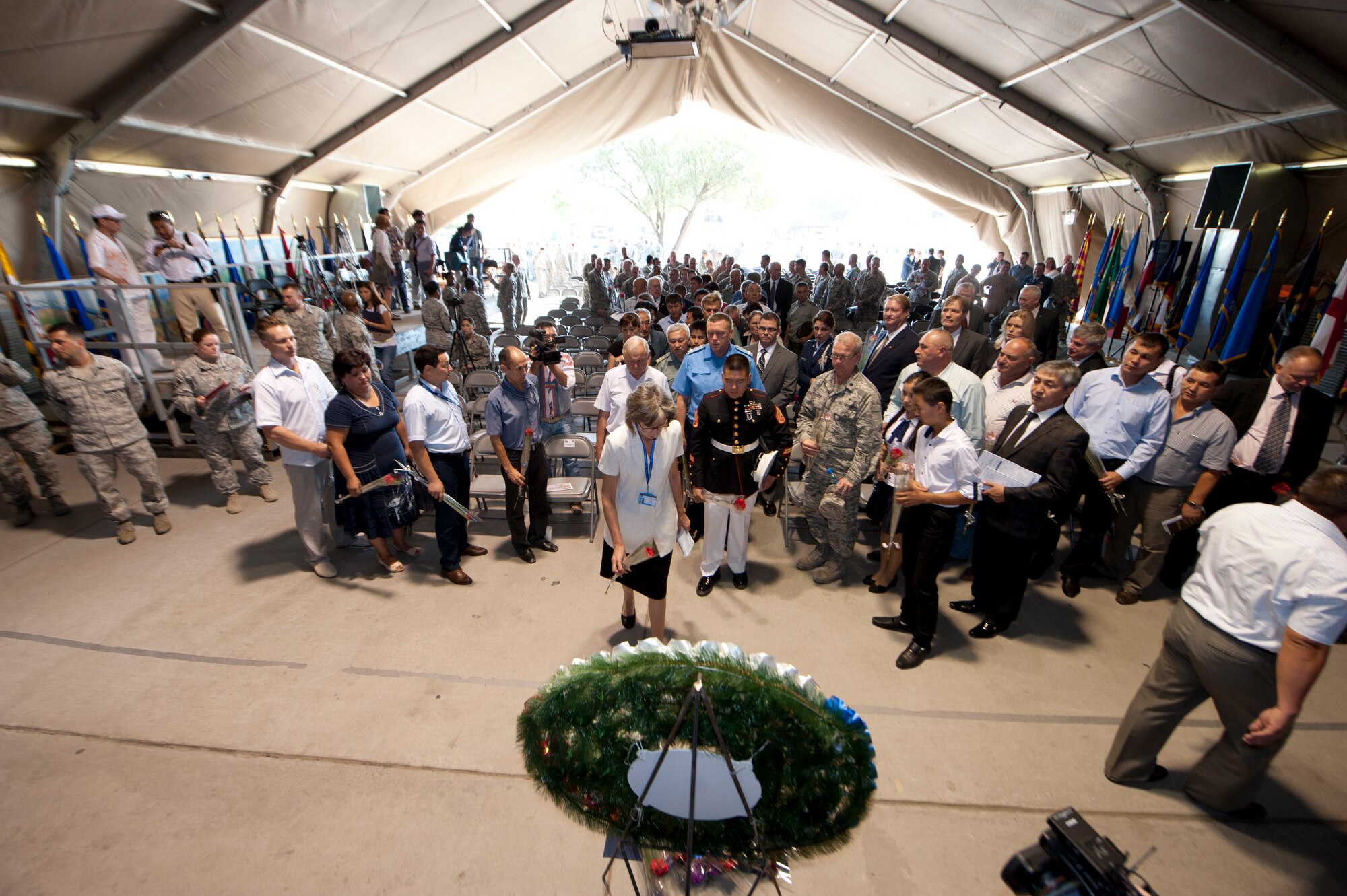 Audience members place flowers before a wreath memorial during the 9/11 Memorial Ceremony at Transit Center at Manas, Kyrgyzstan, Sept. 11, 2013. The ceremony remembered those who perished in the tragic event on Sept. 11, 2001 and in the years since.. (U.S. Air Force photo/Staff Sgt. Robert Barnett)