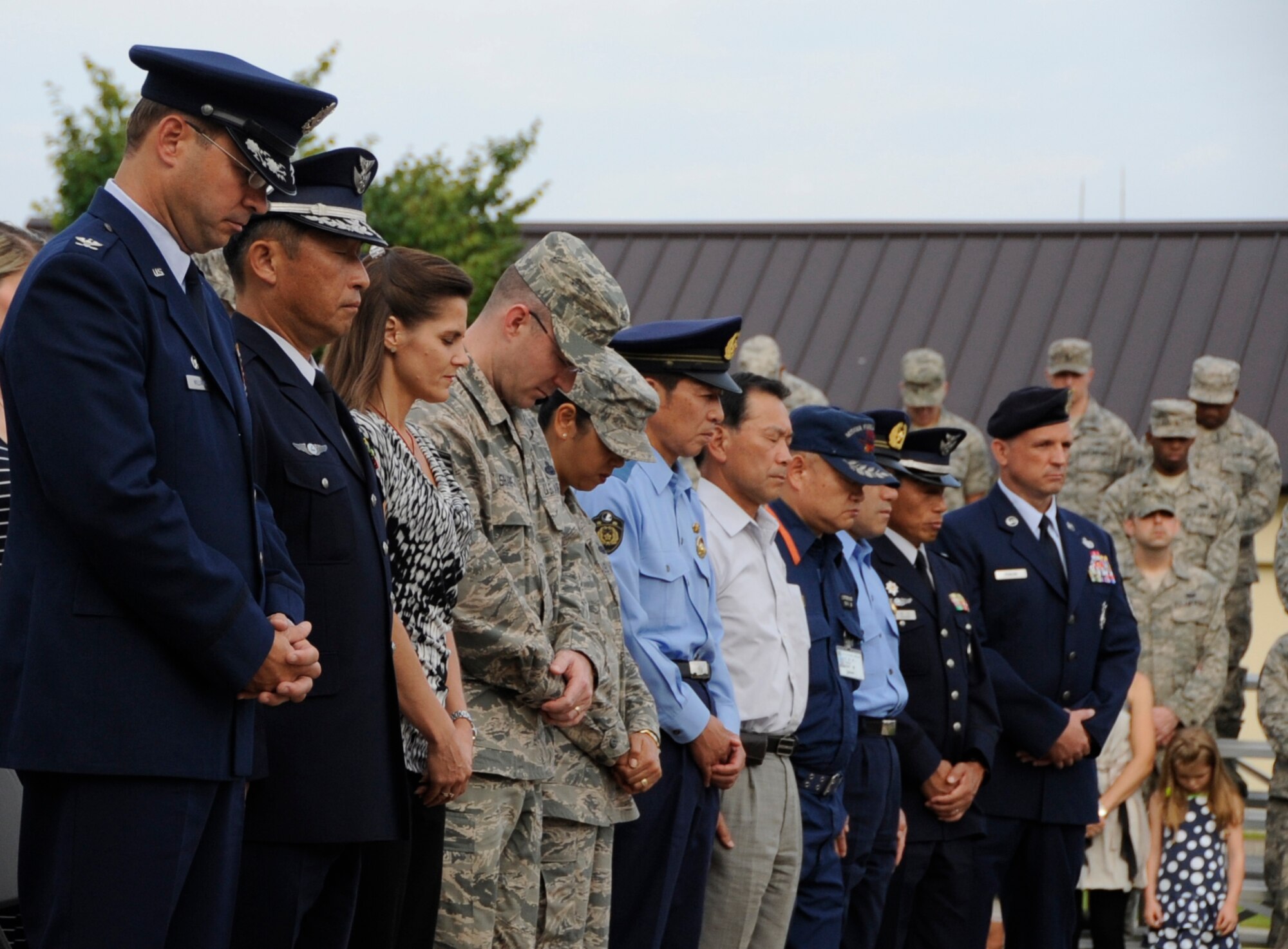 Attendees of the Patriot Day Retreat ceremony take a moment of silence at Misawa Air Base, Japan, Sept. 11, 2013. Twelve years ago, four passenger airliners were hijacked by terrorists and flown into buildings in suicide attacks. Service members here took time to remember the thousands of people that lost their lives, as well as the acts of heroism from first-responders. (U.S. Air Force photo by Airman 1st Class Kaleb Snay)