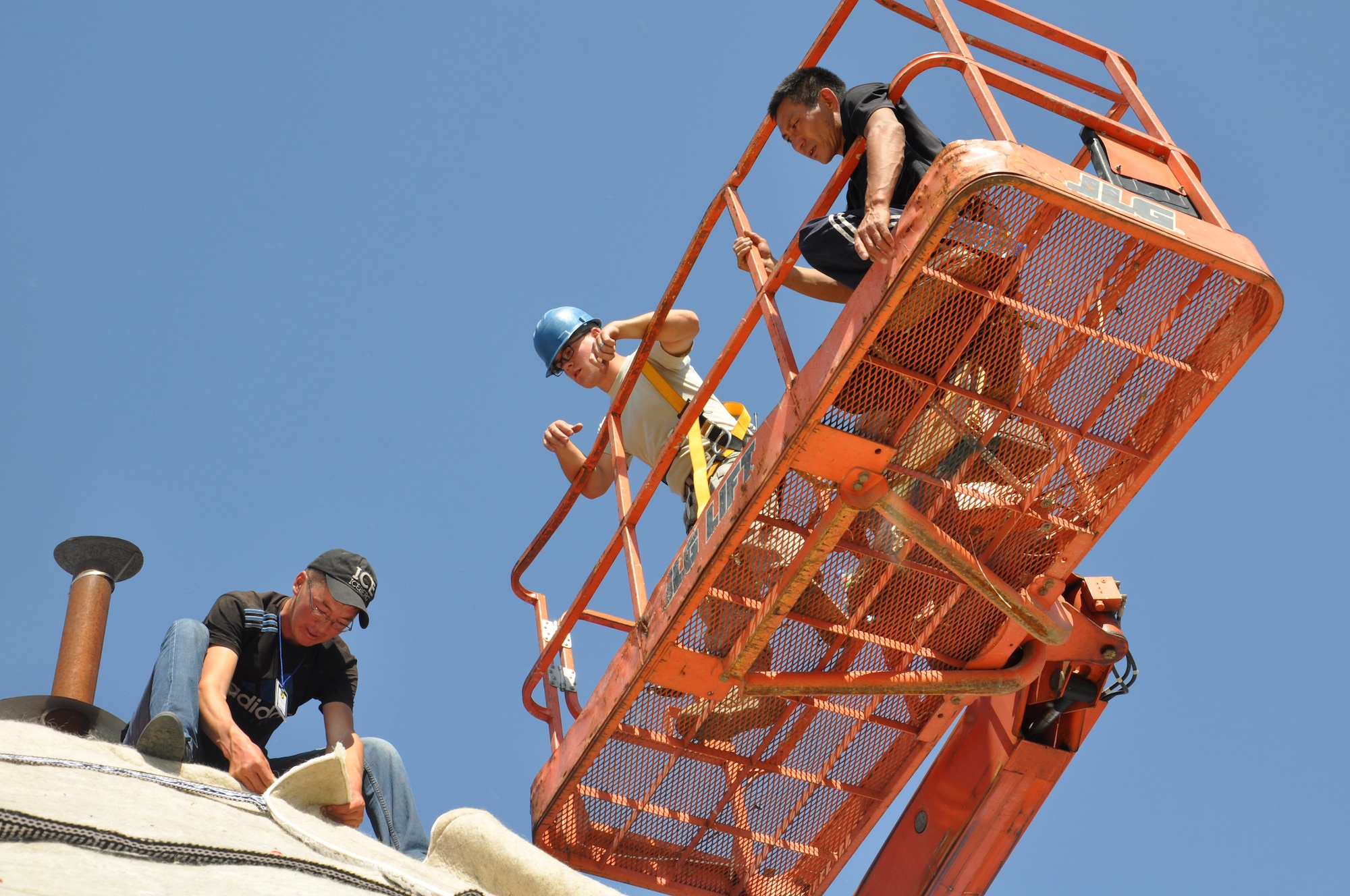Senior Airman Chris Francis of the 376th Expeditionary Civil Engineer Squadron, middle, takes two skilled yurt builders up 17-feet on an aerial man lift to stretch the new sheep wool cover over the Yurt roof at the Transit Center at Manas, Kyrgyzstan on Sept. 7, 2013. The traditional nomadic yurt stands as an authentic representation of the Kyrgyz culture on the military installation. Francis is a structural engineer deployed from Minot Air Force Base, N.D., and is native of Greenville, Ohio. (U.S. Air Force photo/Master Sgt. Donna T. Jeffries)