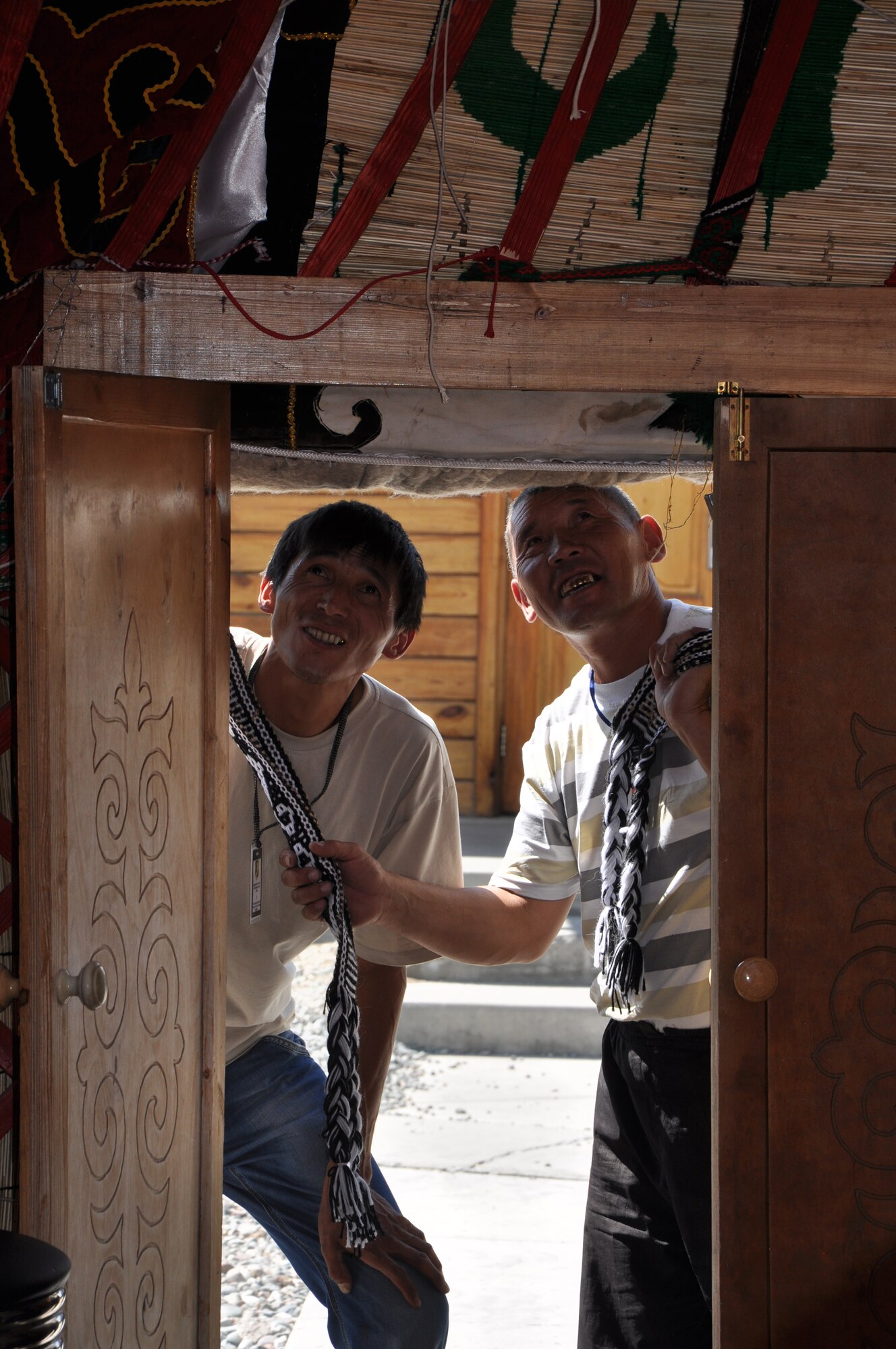 Ismailov Eridan and Abdraev Kenjebek, skilled Kyrgyz yurt builders, take a look at their handiwork done to upgrade the covering of the nomadic tent on the Transit Center at Manas on Sept. 7, 2013. A crew of five laborers from the Issyk-Kul Lake region traveled four hours to complete this specialized job. Yurts have been the traditional home in Central Asia for thousands of years. (U.S. Air Force photo/Master Sgt. Donna T. Jeffries)