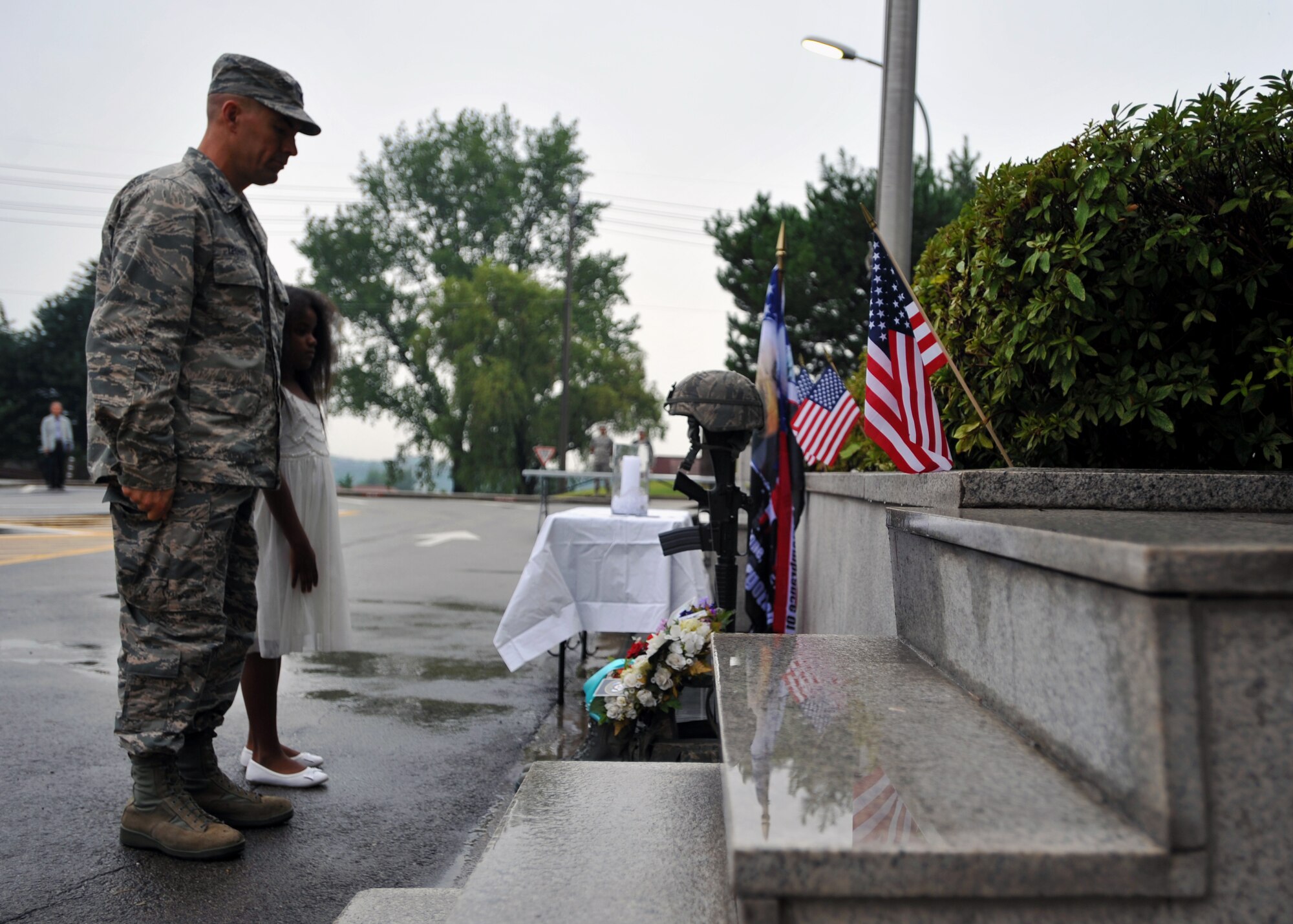 Col. Brook Leonard, 51st Fighter Wing commander, and Makalya Washington, daughter of Master Sgts. Mark and Loretta Washington, pay their respects at a 9/11 memorial during a ceremony at Osan Air Base, Republic of Korea, Sept. 11, 2013. At the end of the ceremony, Leonard’s message to everyone in attendance was simply to “never forget” and to use that day to strengthen their dedication to the core values. (U.S. Air Force photo/Senior Airman Siuta B. Ika)