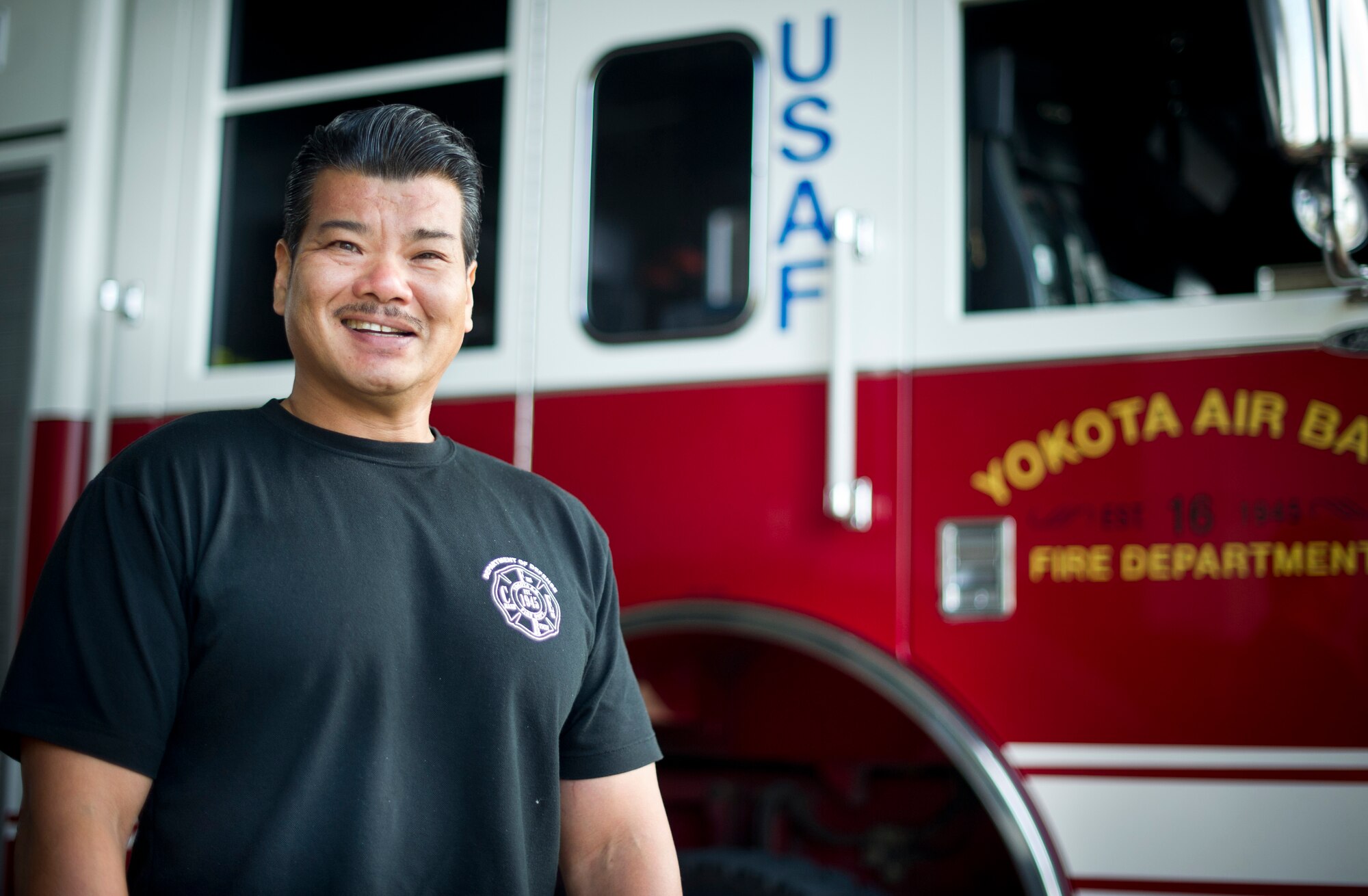 Kazuhisa Iizuka, 374th Civil Engineer Squadron Fire Department crew chief, is photographed in front of a fire truck Sept. 6, 2013, at Yokota Air Base, Japan. Iizuka and fellow firefighters Senior Airmen Thomas Kirts and Jonathan Douglas performed life saving CPR to a woman at the Fussa International Festival Aug. 31, 2013. (U.S. Air Force photo by Staff Sgt. Stacy Moless/Released)
