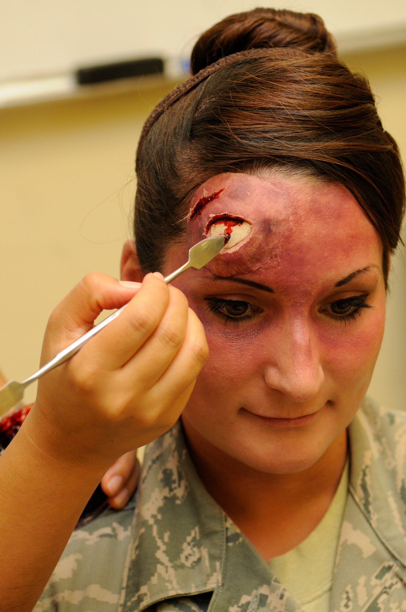 U.S. Air Force Staff Sgt. Evelyn Sanchez-Jalomo, 18th Dental Squadron dental laboratory craftsman, applies fake blood to simulate a head wound on Senior Airman Jessica Ashe, 18th Force Support Squadron assistant sports director, during a local operational readiness exercise on Kadena Air Base, Japan, Sept. 11, 2013. The simulated wounds are made to look as realistic as possible to ensure personnel respond more accurately while treating the victim. (U.S. Air Force photo by Senior Airman Marcus Morris)