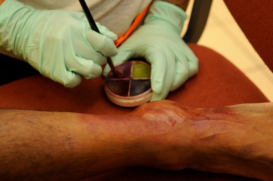 U.S. Air Force Staff Sgt. Evelyn Sanchez-Jalomo, 18th Dental Squadron dental laboratory craftsman, applies make-up to simulate a bruised ankle on Airman 1st Class Dejon Williams, 18th Communications Squadron cyber transfer journeyman, during a local operational readiness exercise on Kadena Air Base, Japan, Sept. 11, 2013. Sanchez-Jalomo creates realistic wounds for self-aid buddy care that would be seen in real wartime conditions. (U.S. Air Force photo by Senior Airman Marcus Morris)