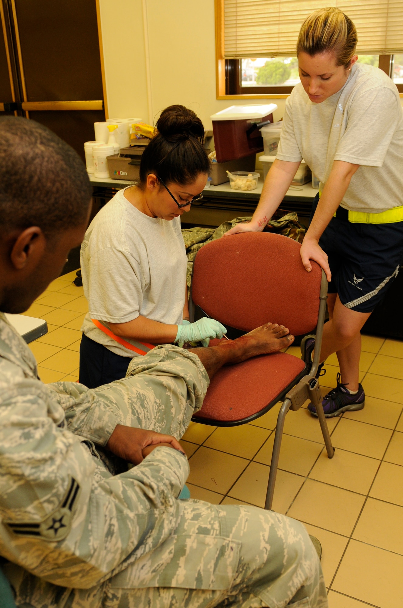 U.S. Air Force Staff Sgt. Evelyn Sanchez-Jalomo, 18th Dental Squadron dental laboratory craftsman, applies a mock injury to Airman 1st Class Dejon Williams, 18th Communications Squadron cyber transfer journeyman, while training Staff Sgt. Shannon Almero, 18th Aerospace Medical Squadron public health craftsman, during a local operational readiness exercise on Kadena Air Base, Japan, Sept. 11, 2013. Moulage allows Airmen to train for real world self-aid buddy care scenarios. (U.S. Air Force photo by Senior Airman Marcus Morris) 