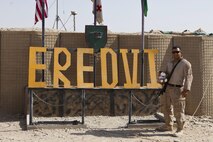 Sgt. Anthony Ortiz, a California native and combat cameraman with Combat Logistics Regiment 2, Regional Command (Southwest), poses with a teddy bear at the sign for Combat Outpost Eredvi, Helmand province, Afghanistan, Aug. 13, 2013. Ortiz took the doll with him during his missions in the province before sending it home to his daughter for her third birthday.
