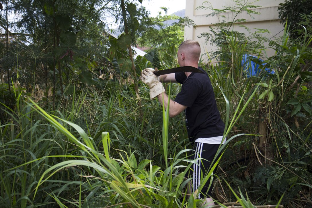 U.S. Marine Corps Cpl. Conor McGrath, company radio operator from Branchville, N.J., assigned to Company K, Battalion Landing Team 3/2, 26th Marine Expeditionary Unit (MEU), clears out overgrown shrubbery as he takes part in an event to clean up and repaint a school in Beau Vallon, Seychelles, Aug. 26, 2013. The 26th MEU is a Marine Air-Ground Task Force forward-deployed to the U.S. 5th Fleet area of responsibility aboard the Kearsarge Amphibious Ready Group serving as a sea-based, expeditionary crisis response force capable of conducting amphibious operations across the full range of military operations. (U.S. Marine Corps photo by Cpl. Michael S. Lockett/Released)