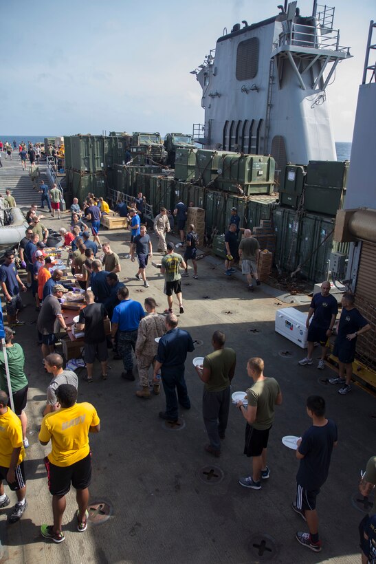 U.S. Marines and Sailors assigned to the 26th Marine Expeditionary Unit (MEU) and USS Carter Hall (LSD 50) relax out of uniform and enjoy a cookout on the flight deck of the USS Carter Hall while at sea, Aug. 31, 2013. The 26th MEU is a Marine Air-Ground Task Force forward-deployed to the U.S. 5th Fleet area of responsibility aboard the Kearsarge Amphibious Ready Group serving as a sea-based, expeditionary crisis response force capable of conducting amphibious operations across the full range of military operations. (U.S. Marine Corps photo by Cpl. Michael S. Lockett/Released)